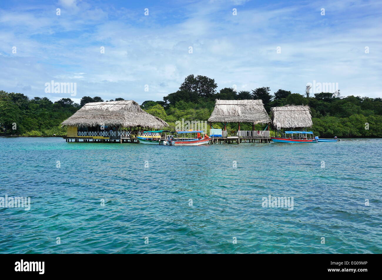 Ristorante tropicale con tetto di paglia sopra l'acqua e imbarcazioni al dock, Caraibi, Bocas del Toro, America centrale e di Panama Foto Stock