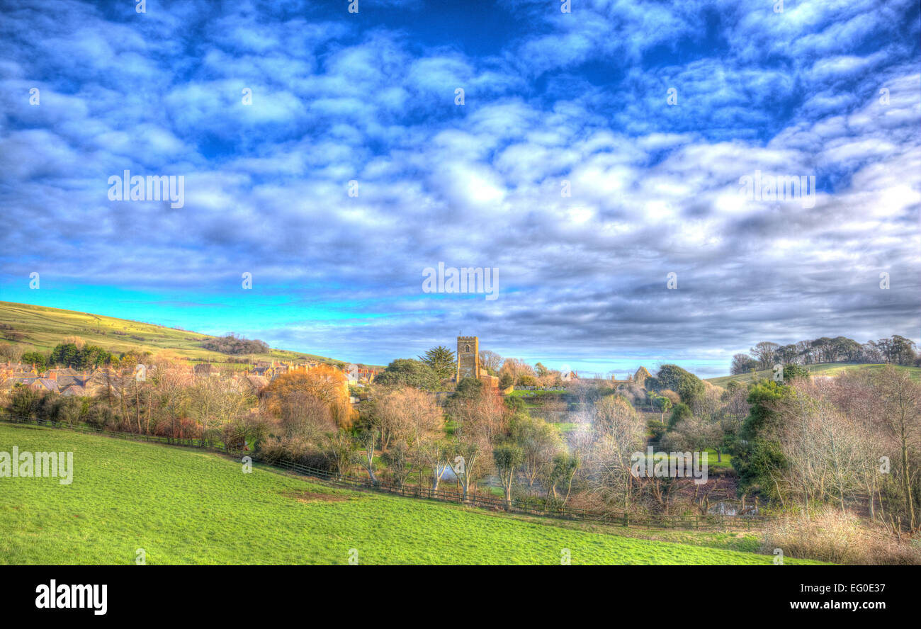 Villaggio Inglese di Abbotsbury Dorset UK impostato in campagna con le mucche e una chiesa come un dipinto in vividi colori luminosi HDR Foto Stock