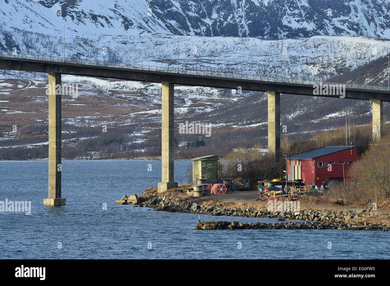 Buildung presso la riva del suono nei pressi del ponte di Andøy nella parte anteriore dei pendii delle montagne innevate, 26 Febbraio 2014 Foto Stock