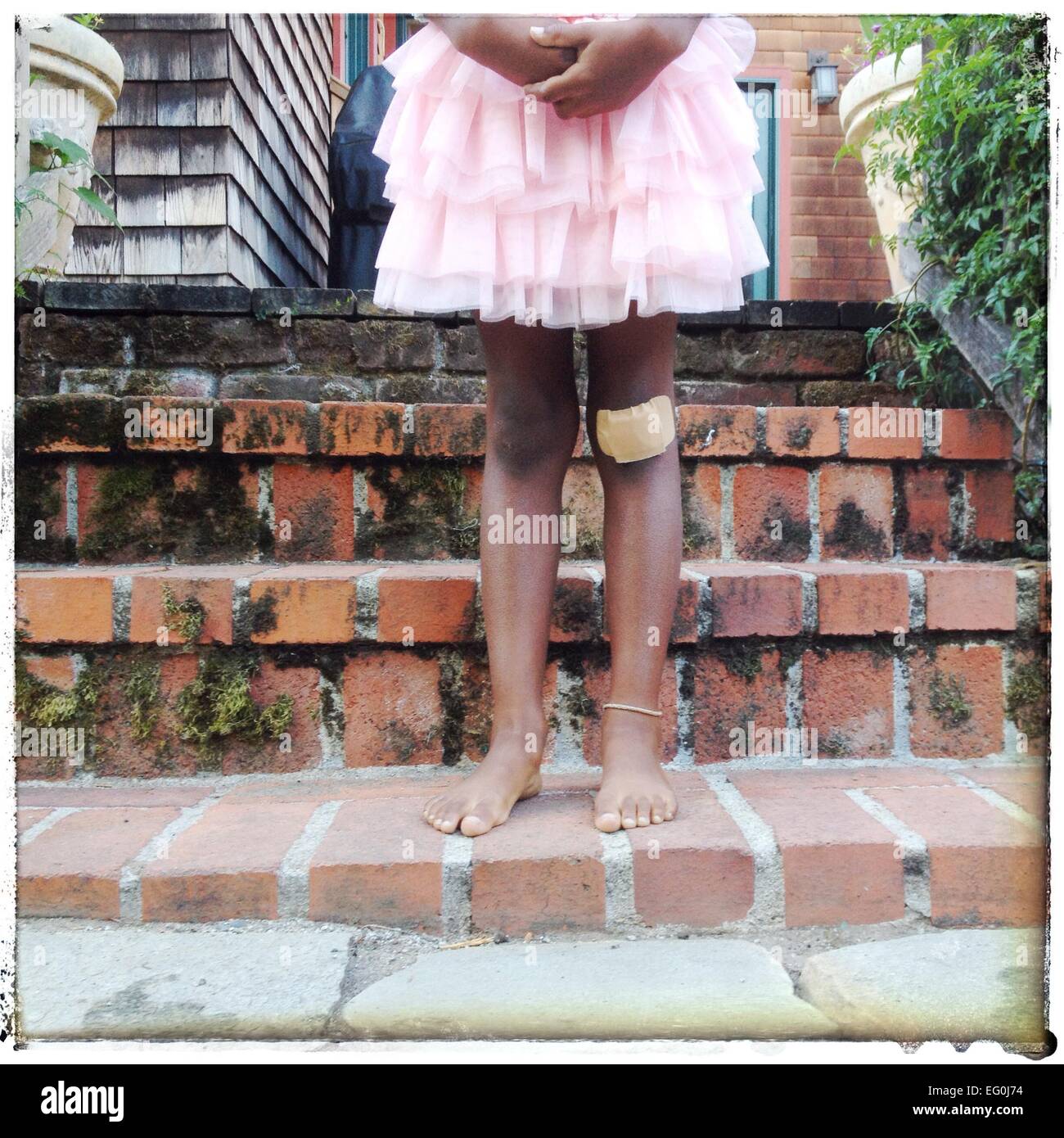 Ragazza con aiuto di banda sul suo ginocchio Foto Stock