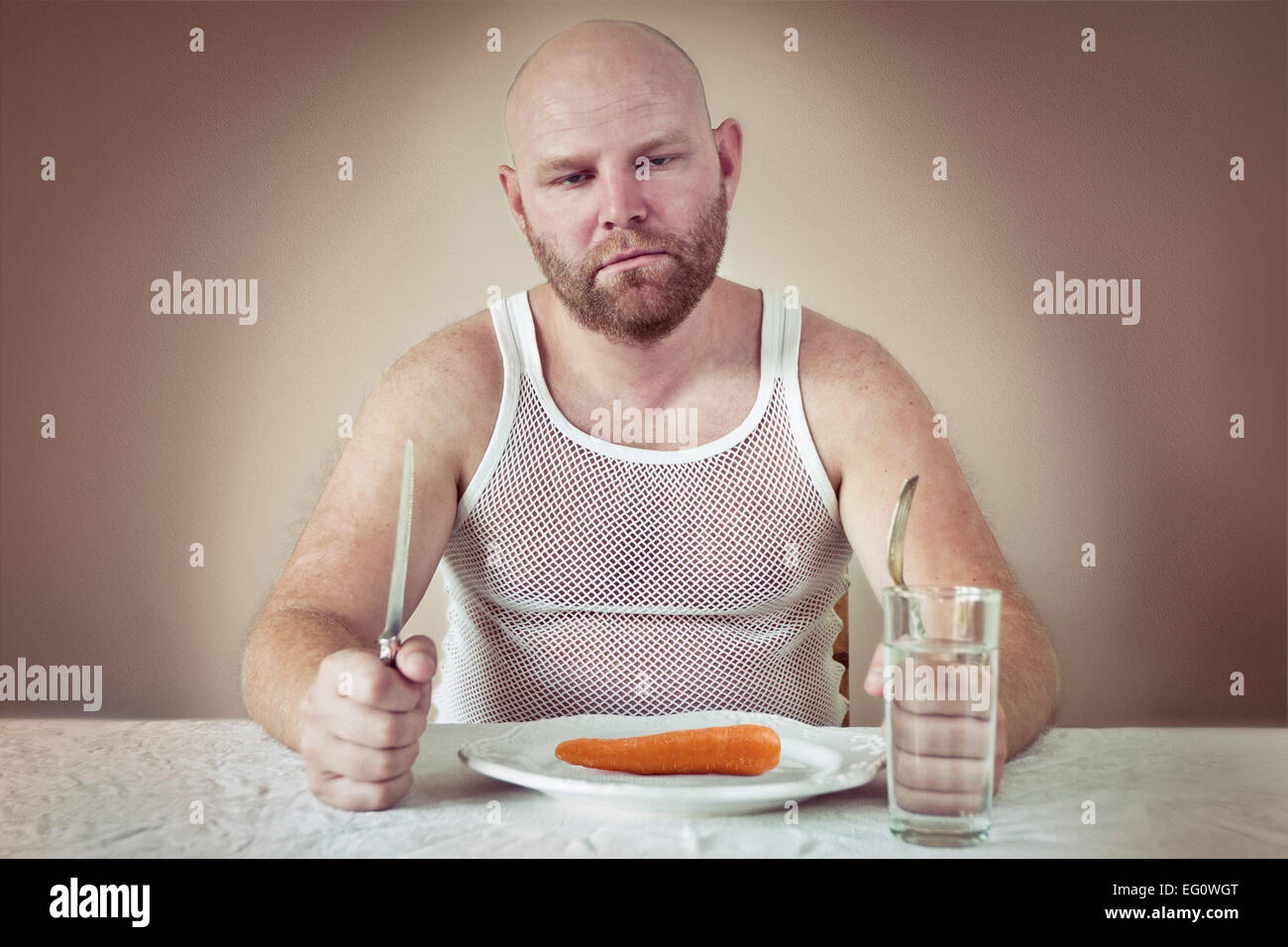 Uomo affamato con solo una carota sulla sua piastra. Perphas su una dieta? Foto Stock