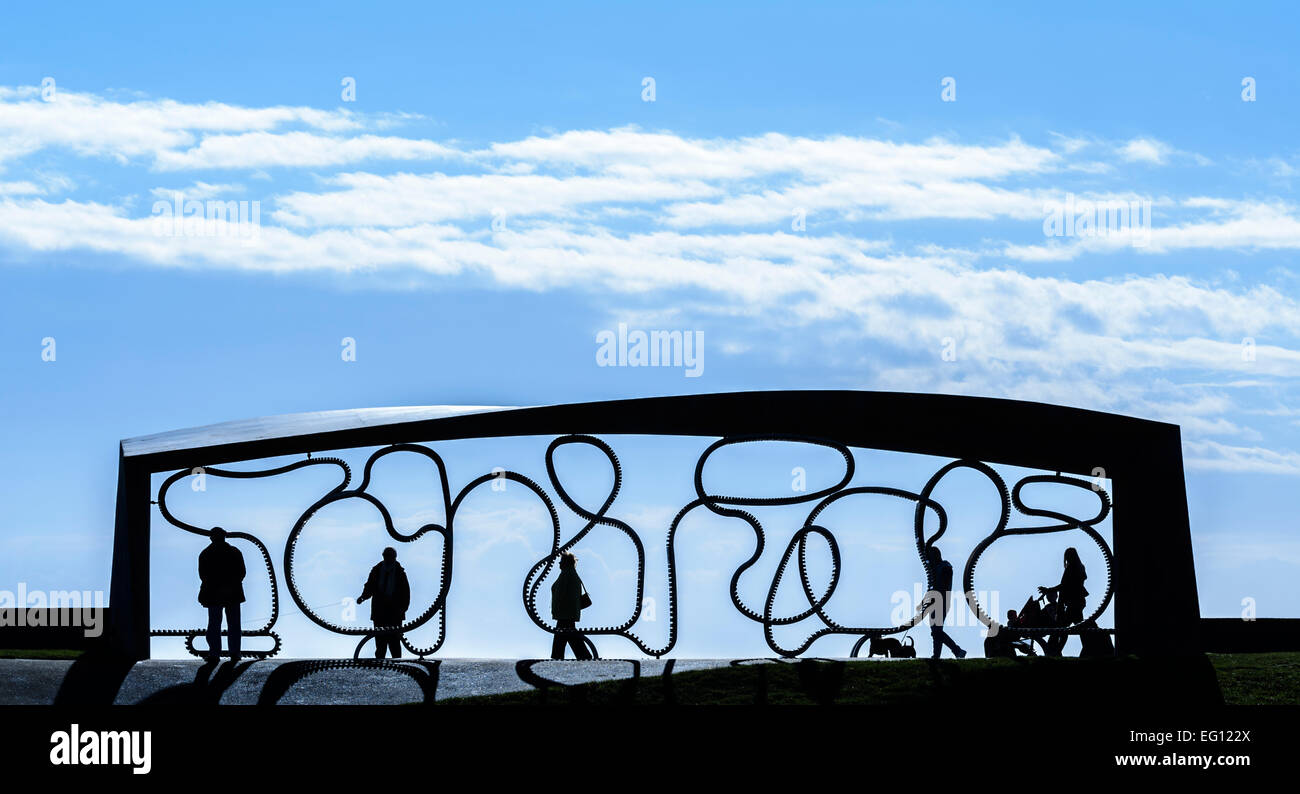 Silhouette di un rifugio e una lunga panca contro il cielo blu sul lungomare a Littlehampton, West Sussex, in Inghilterra, Regno Unito. Foto Stock