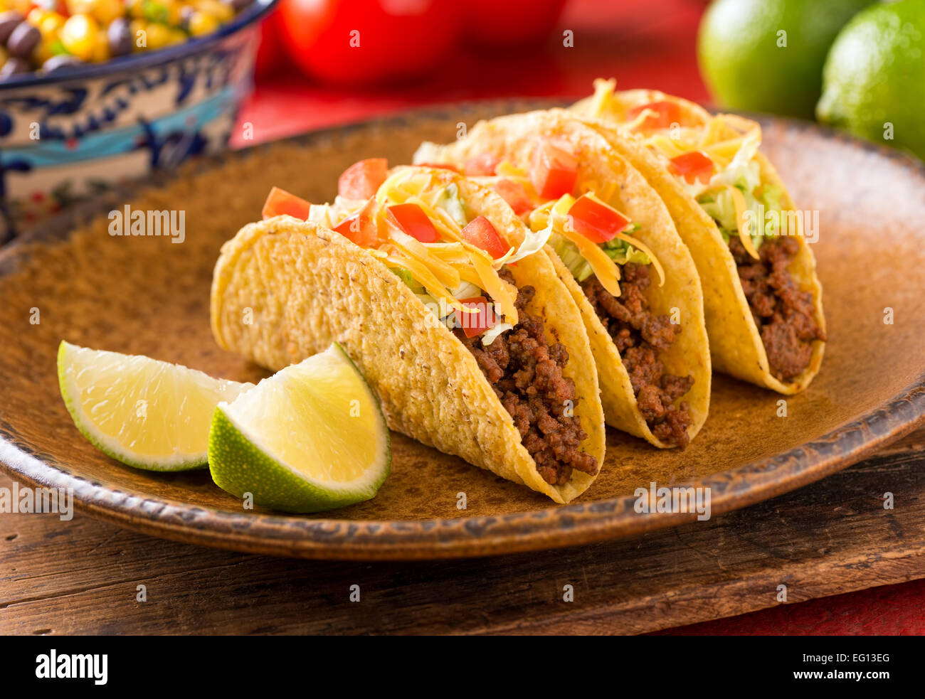 Una piastra di deliziosi tacos con calce, pomodori, lattuga e formaggio. Foto Stock
