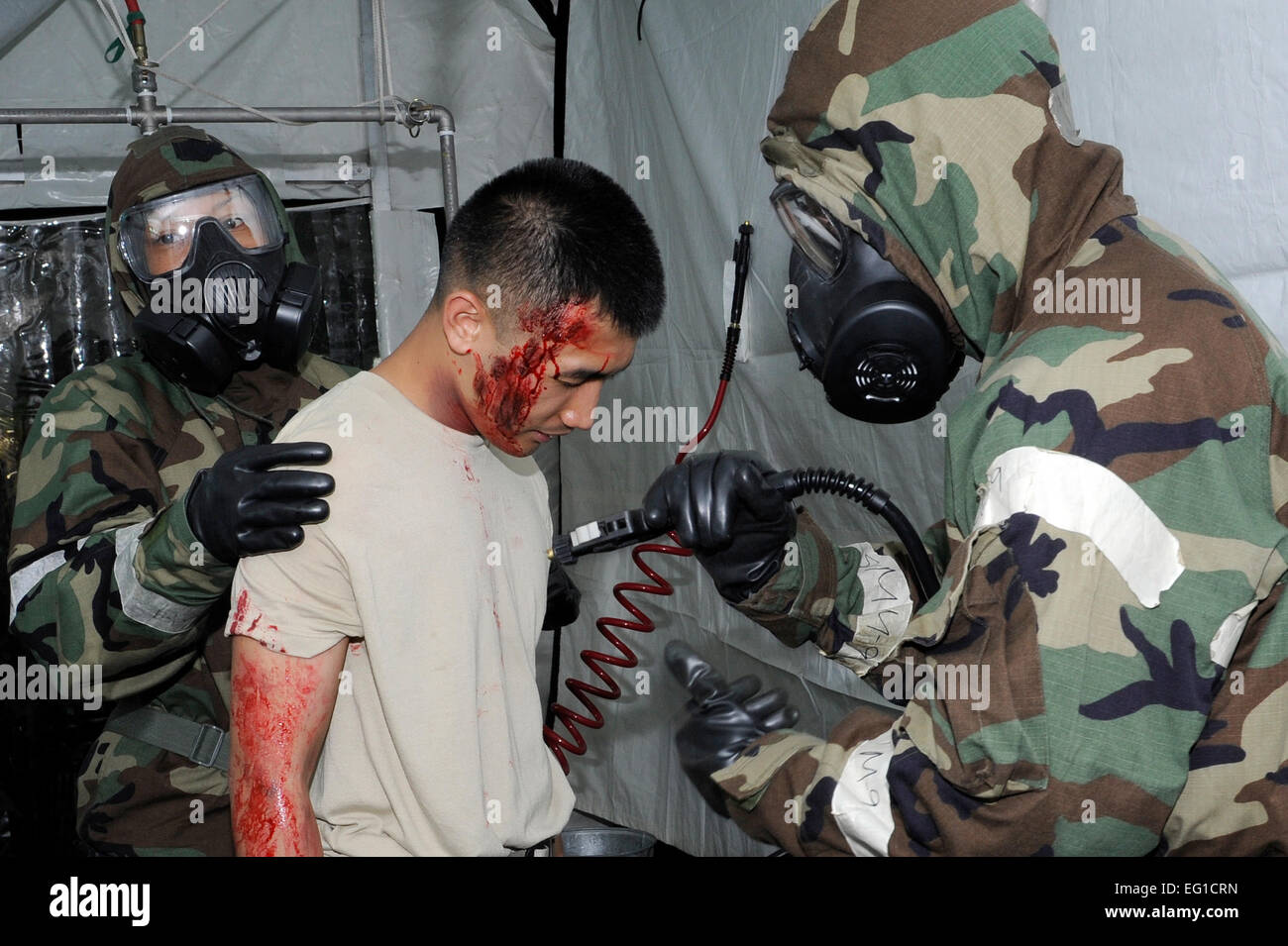 La decontaminazione ai membri del team di simulare la decontaminazione di Air Force Staff Sgt. Duane Valdez, un trentacinquesimo squadrone di comunicazione a radio frequenza sistema di trasmissione tecnico, prima di procedere al trasporto di lui alla tenda medica per il trattamento durante un esercizio a Misawa combatté Air Base, Giappone, 21 giugno 2011. Durante l'esercitazione, avieri praticato il funzionamento in un ambiente di combattimento. Il personale Sgt. Marie Brown Foto Stock