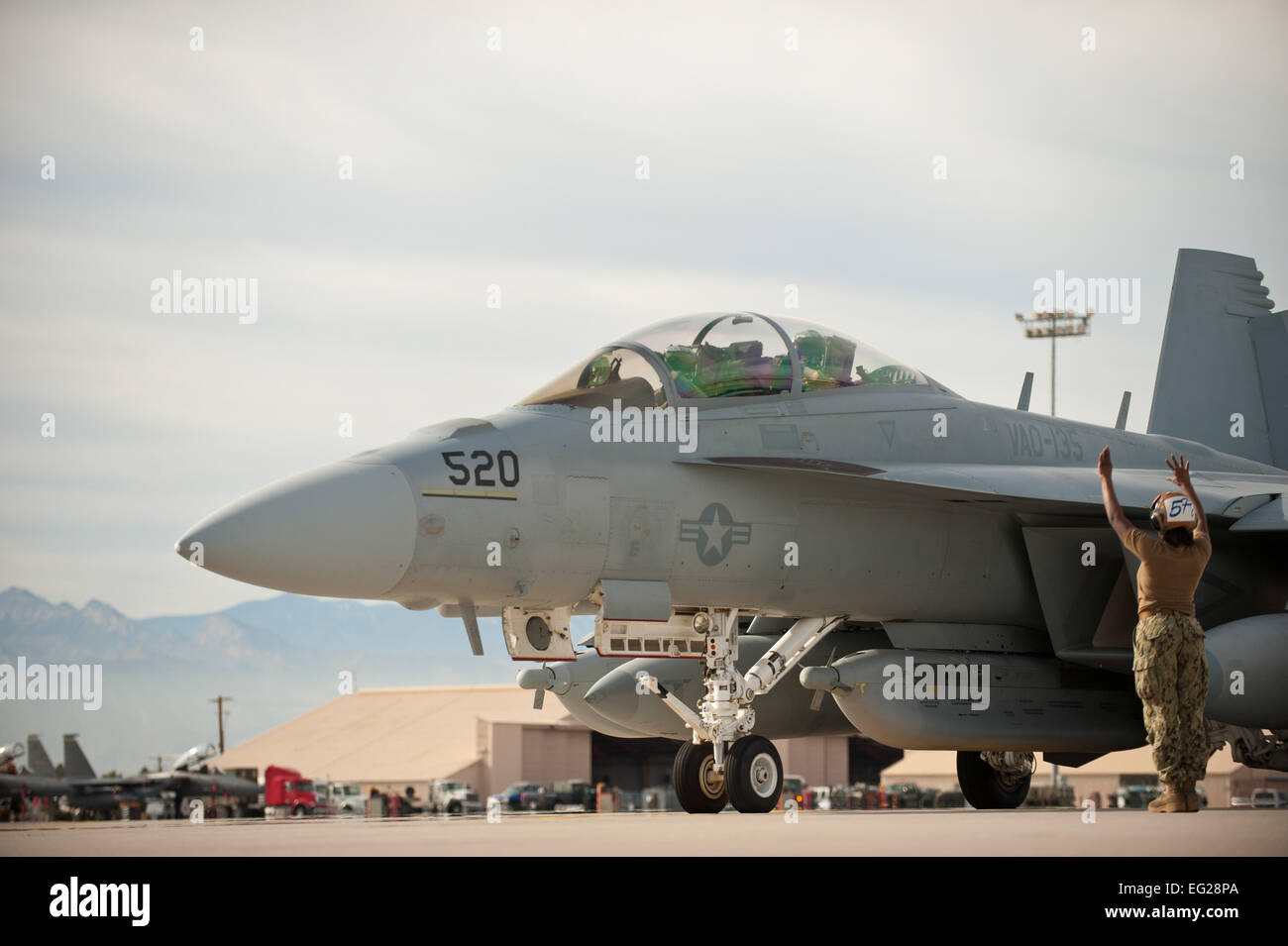 Stati Uniti Navy Petty Officer di terza classe Michea Smith, 135Attacco Elettronico squadrone capitano di volo, Naval Air Station Whidbey Island, nello Stato di Washington, dirige il pilota di un EA-18G Growler al di fuori di un posto auto prima di una missione di addestramento Gen 29, 2014, alla Nellis Air Force Base. Nev. La Boeing EA-18G Growler è un americano di carrier-based electronic warfare aeromobili, una versione specializzata del due-sede F/A-18F Super Hornet. Bandiera rossa fornisce personale di volo e di aria di operazioni di sostegno i membri del servizio da varie cellule, i servizi militari e i paesi alleati una opportunità per integrare e pratica combattere operat Foto Stock