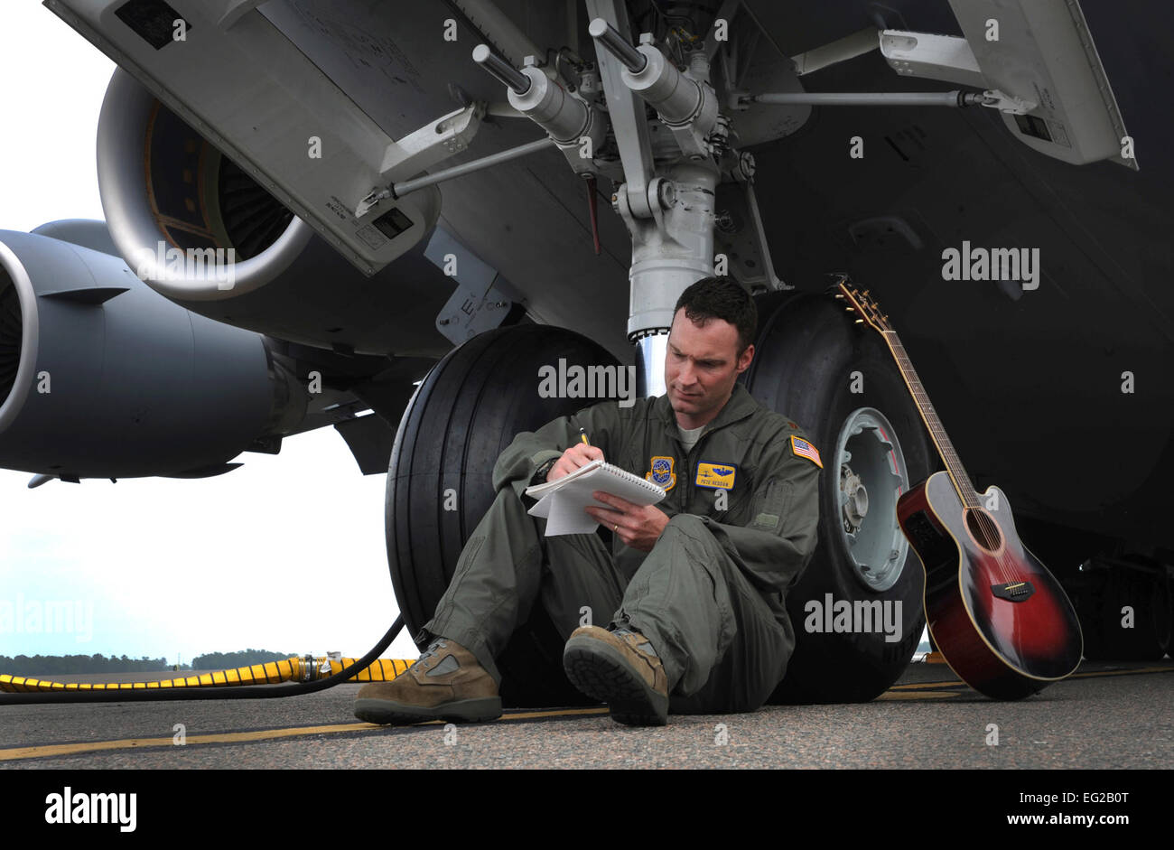 Principali Pete Reddan scrive una canzone mentre appoggiata sulla parte anteriore dei pneumatici di un C-17 Globemaster III a base comune, Charleston S.C., 13 giugno 2012. Reddan militare della melodia ispirata, "No alla guerra", è stato recentemente registrato da Nashville artista di registrazione, Brad Anderson. Il brano è stato ispirato dalla sua esperienza durante le distribuzioni come pure le esperienze degli uomini e delle donne Reddan serve a. Reddan è un 437th Airlift Wing pilota. Airman 1. Classe Ashlee Galloway Foto Stock