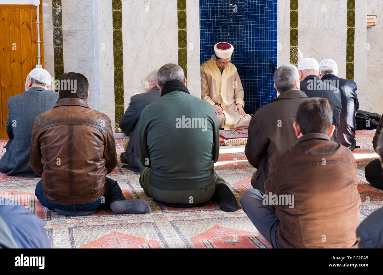 Un imam è seduto e pregando in un mihrab durante il pomeriggio di venerdì la preghiera in una moschea Foto Stock