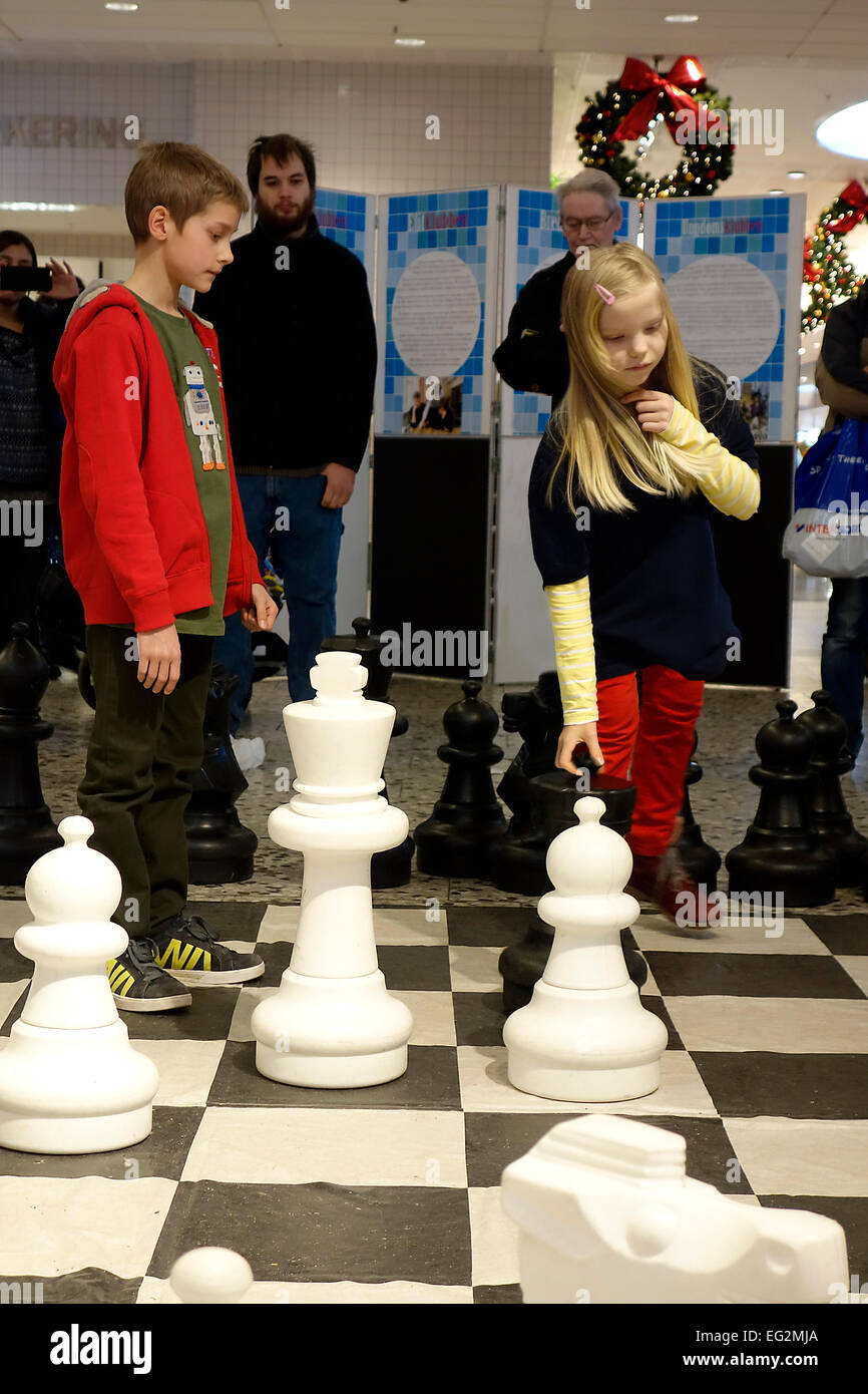10 anni ragazza ragazzo e giocare a scacchi in pubblico con grande giardino di plastica set di scacchi. Nordstan, Göteborg, Svezia Foto Stock