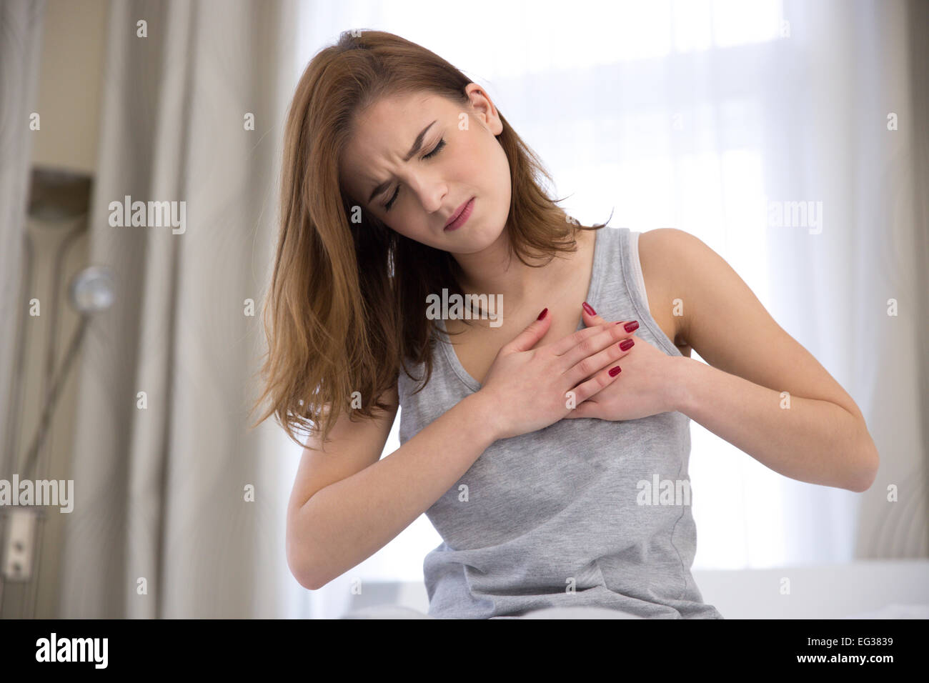 Giovane donna in pigiama avente un attacco di cuore Foto Stock