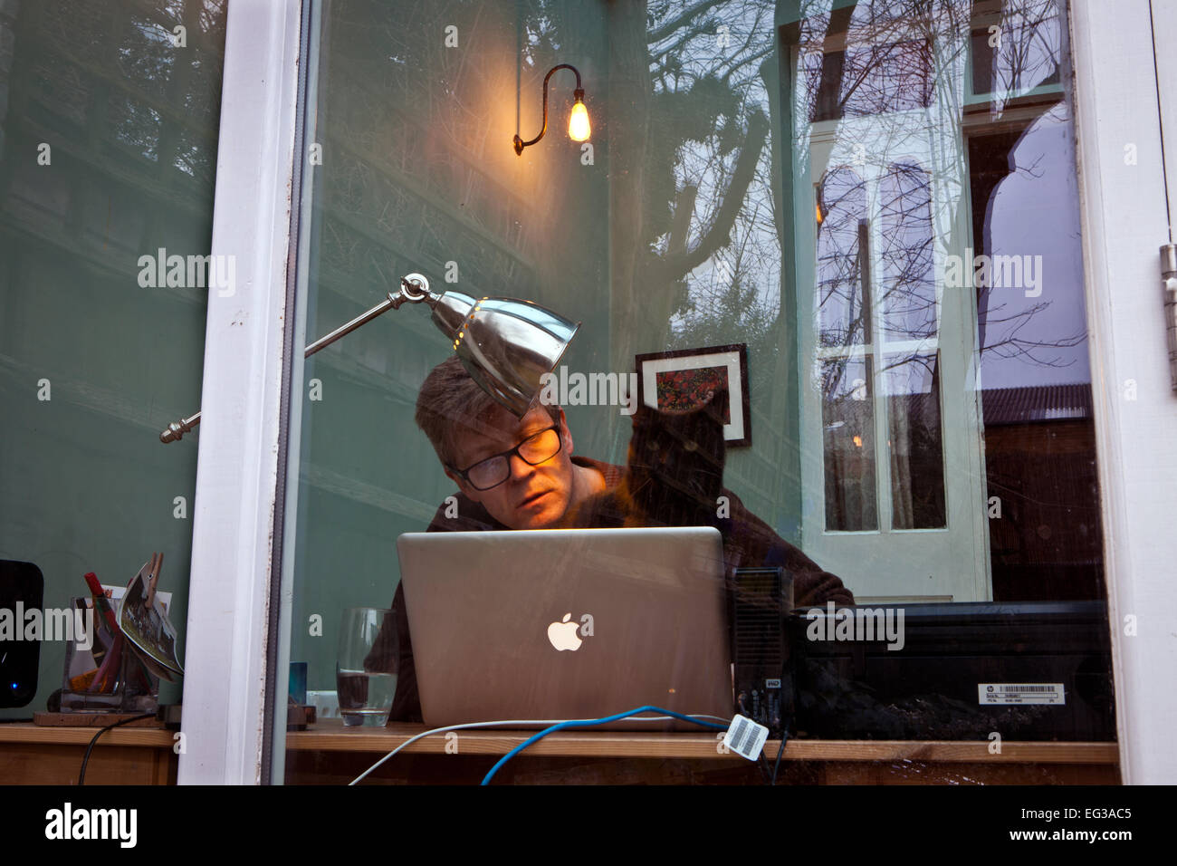 L'uomo visto attraverso una finestra sul laptop computer Apple Mac Foto Stock