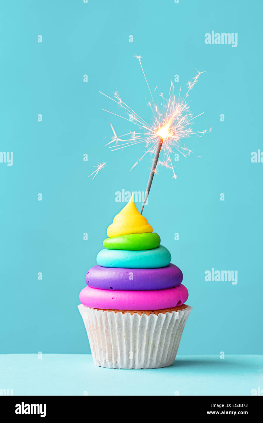 Vivacemente colorato cupcake decorate con un sparkler Foto Stock