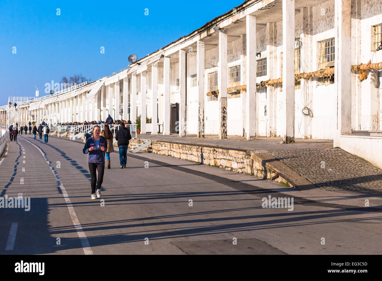 Una giovane donna è visto correre davanti ad un magazzino in disuso nel lungomare sono di savamala, beton hala di Belgrado, in Serbia Foto Stock