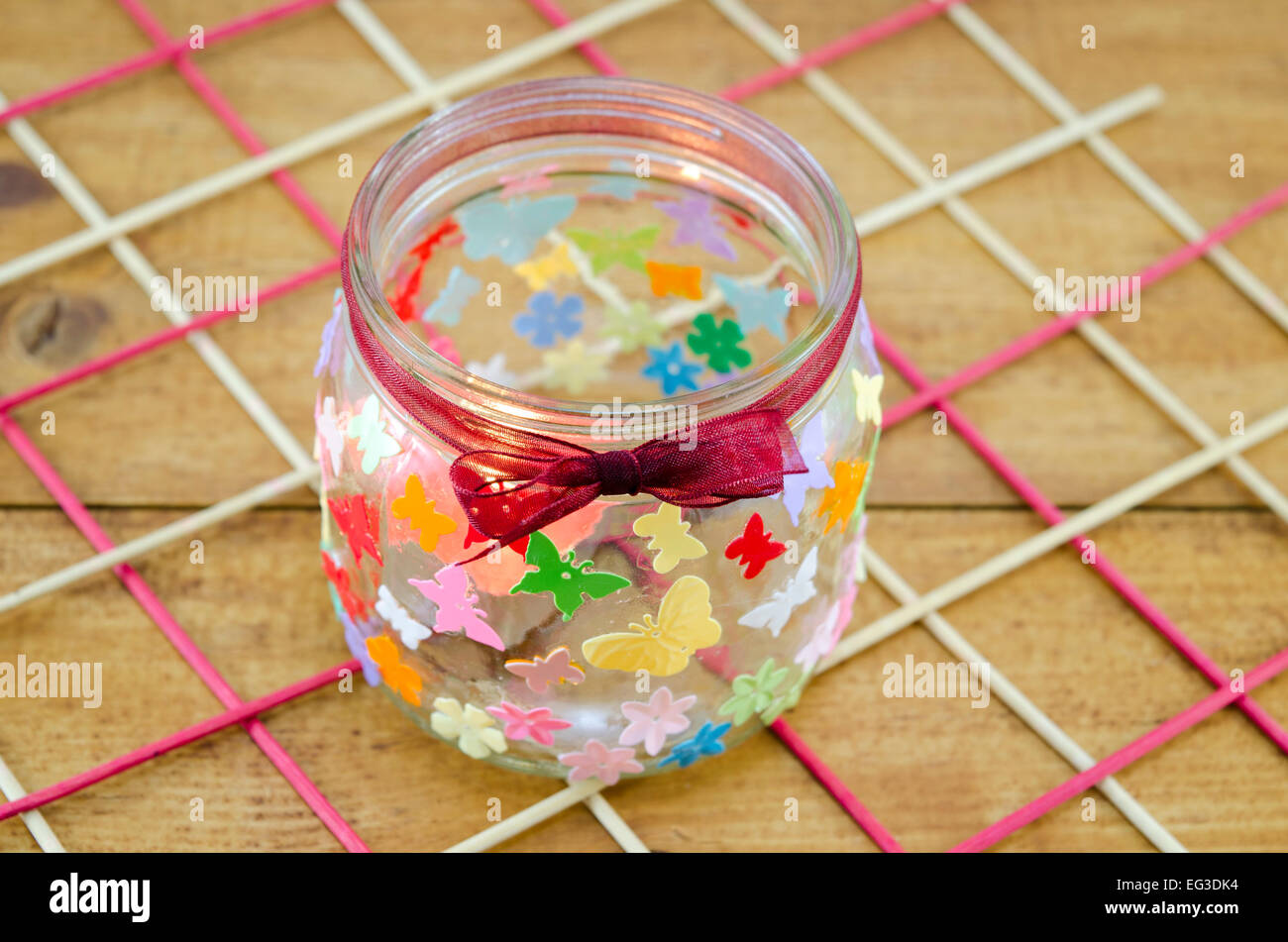 DIY porta candele decorate con coloratissime farfalle su una tavola di legno Foto Stock