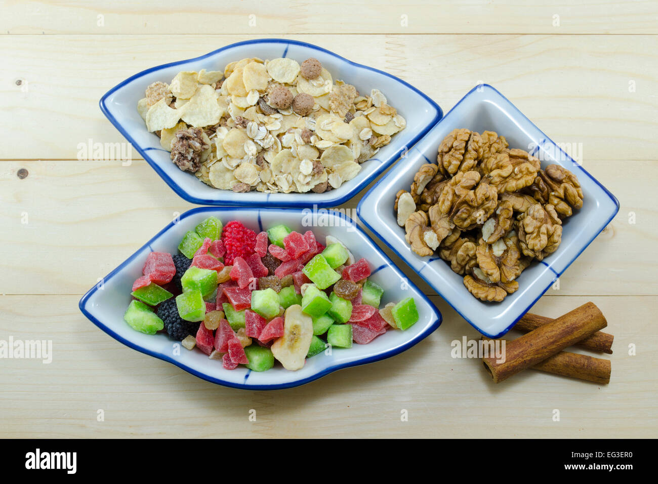 Muesli, di noci e frutta secca e bastoncini di cannella su una tavola di legno Foto Stock