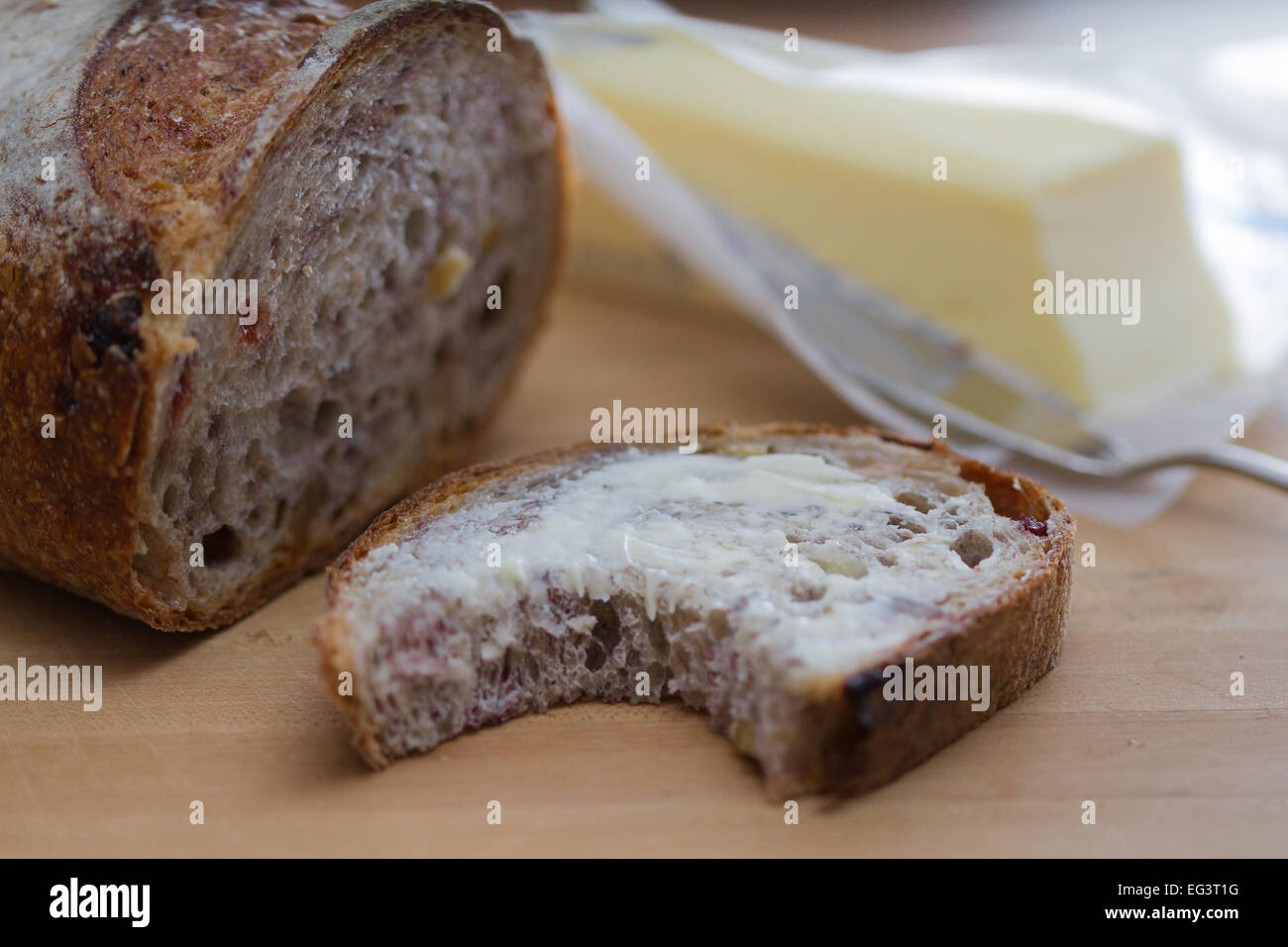 Una fetta di mirtillo palustre imburrato pane alle noci con un morso mancante Foto Stock