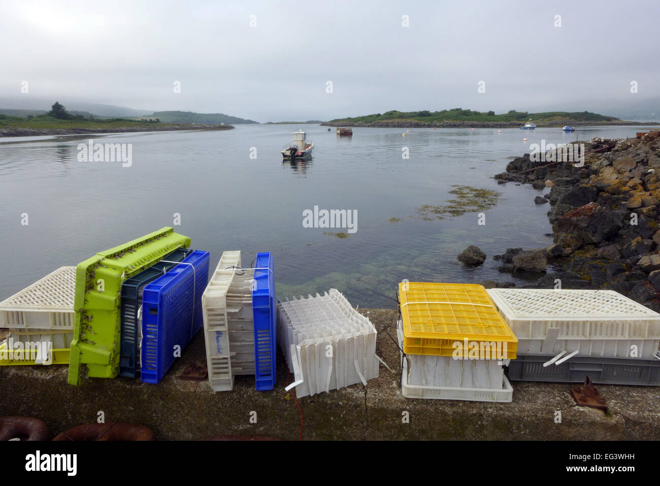 Plastica contenitori di molluschi e crostacei in primo piano su Mull guardando verso Loch Tuath e Eilean a Chaolais. Ulva è a sinistra. Foto Stock