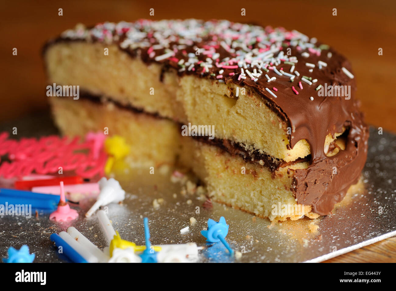 Resti di metà mangiato cioccolato rivestito in spugna Vittoriano con centinaia e migliaia e parte modulo candele festa di compleanno Foto Stock
