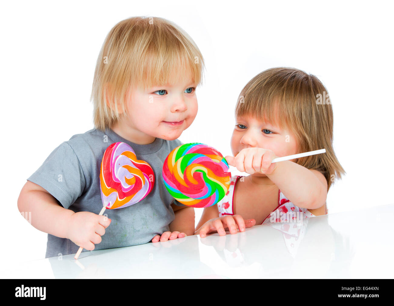 I neonati di mangiare un lecca-lecca appiccicoso su sfondo bianco Foto Stock