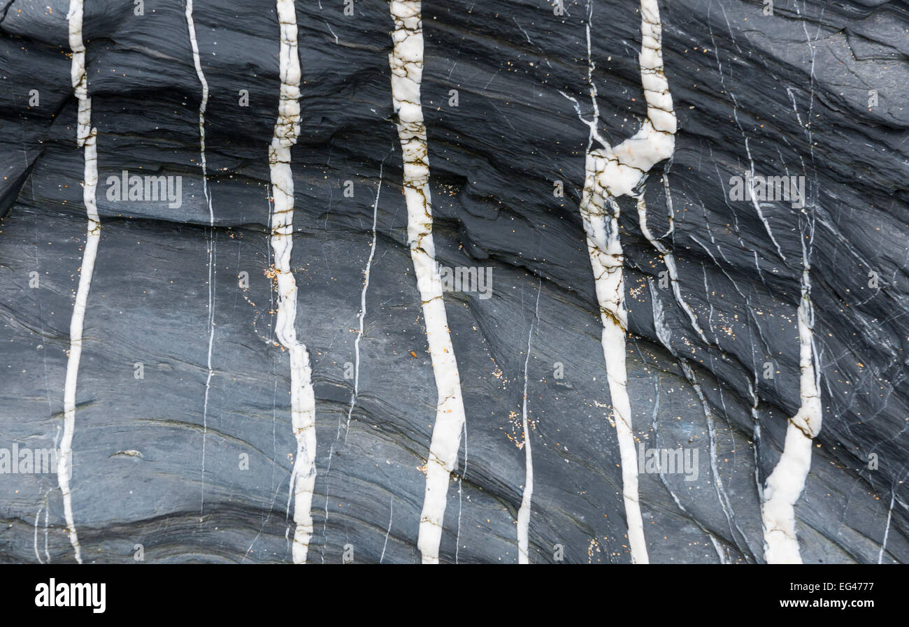 Black rock con diverse strisce bianche e un po' di sabbia. Foto Stock