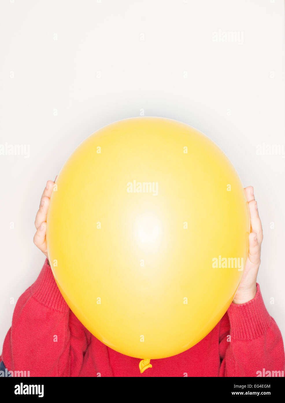 Bambino azienda palloncino giallo nella parte anteriore del viso. Uno stile di vita divertente momento. Foto Stock