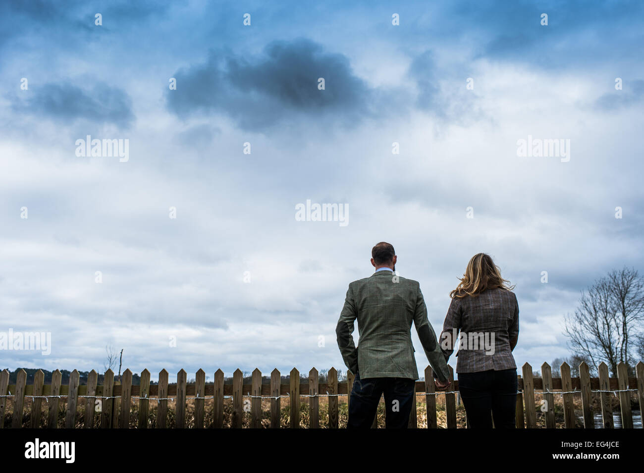 Silhouette sagoma di due persone che si tengono per mano rivolta lontano dalla fotocamera con un cielo atmosferica Foto Stock