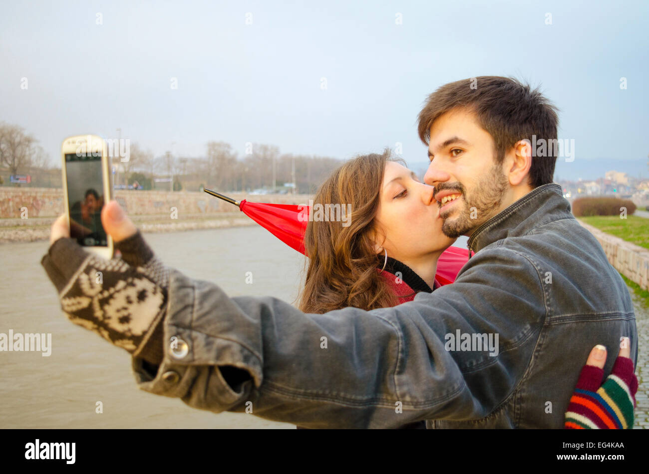 Un ragazzo e una ragazza tenendo un selfie in una piovosa giornata all'aperto Foto Stock