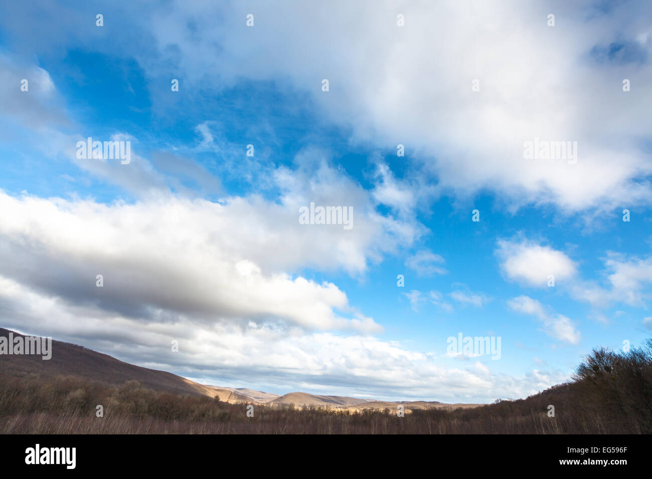 Il cielo blu con nuvole bianche su di bassa montagna del Caucaso a inizio primavera del giorno Foto Stock