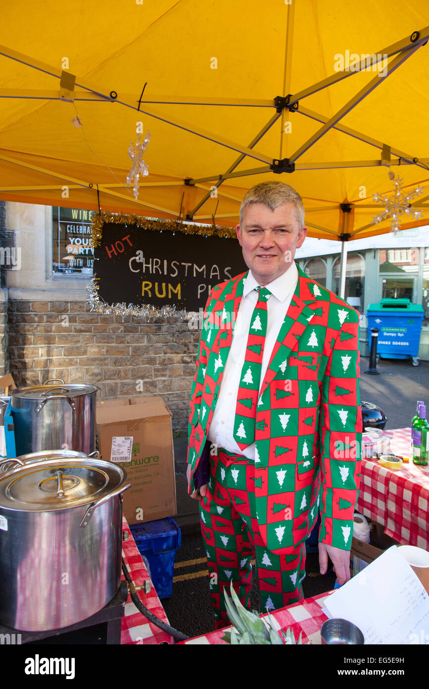 Uomo vestito in un colorato di rosso e verde tuta con albero di Natale design la vendita di bevande in una fase di stallo durante il Natale Haslemere ma Foto Stock