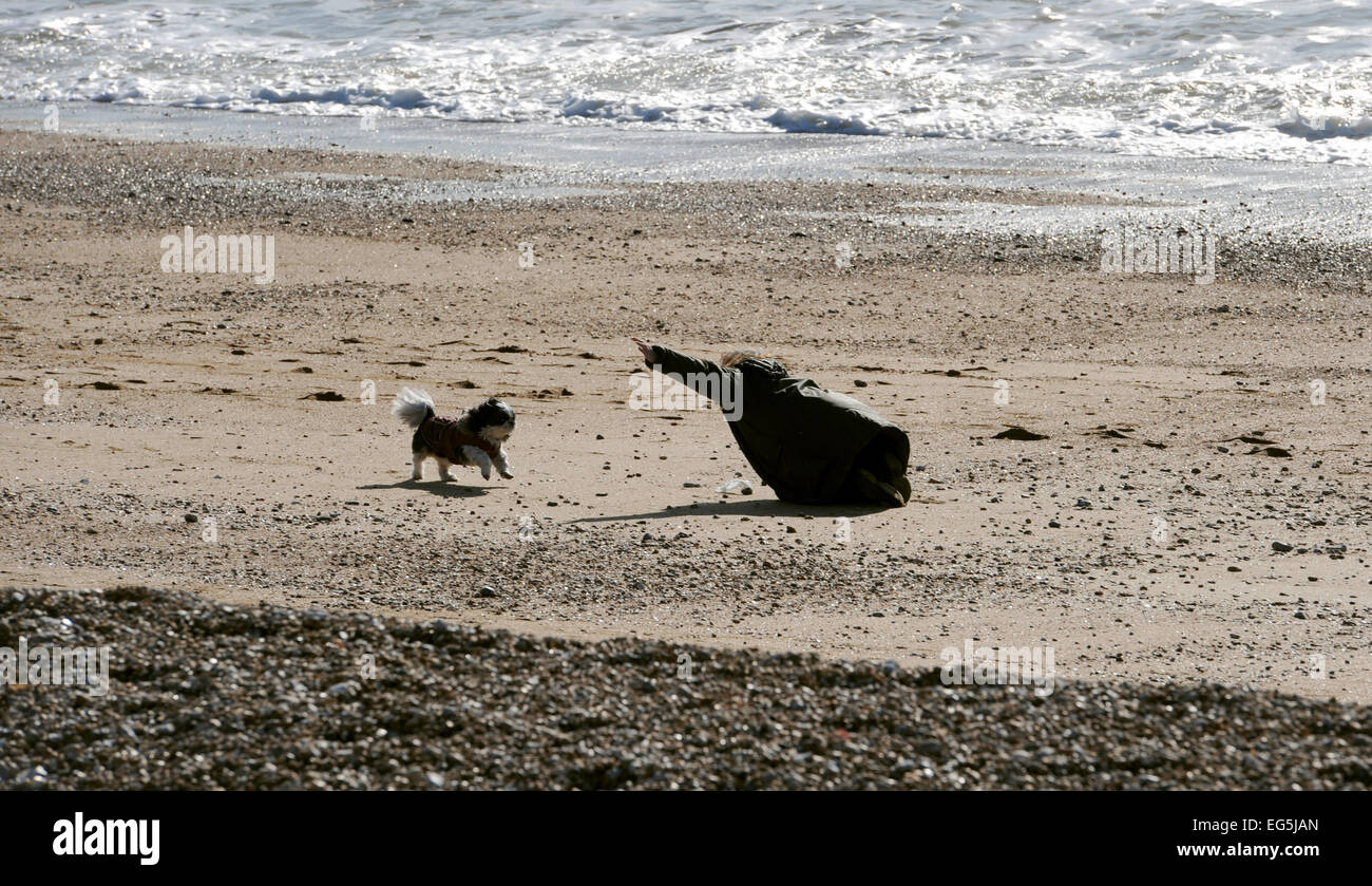 Una donna che gioca con il suo cane sulla spiaggia di Seaford come persone godetevi la calda primavera come meteo sulla costa sud di oggi Foto Stock