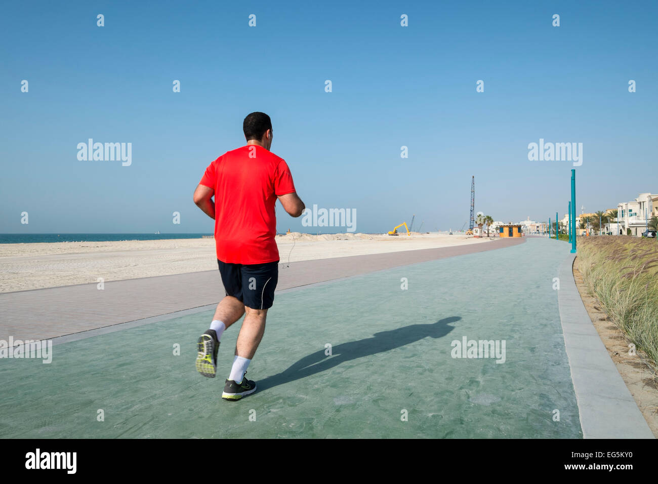Uomo di jogging sul nuovo ristrutturato il jogging e passeggiate via lungo la spiaggia di Umm Suqueim in Dubai Emirati Arabi Uniti Foto Stock