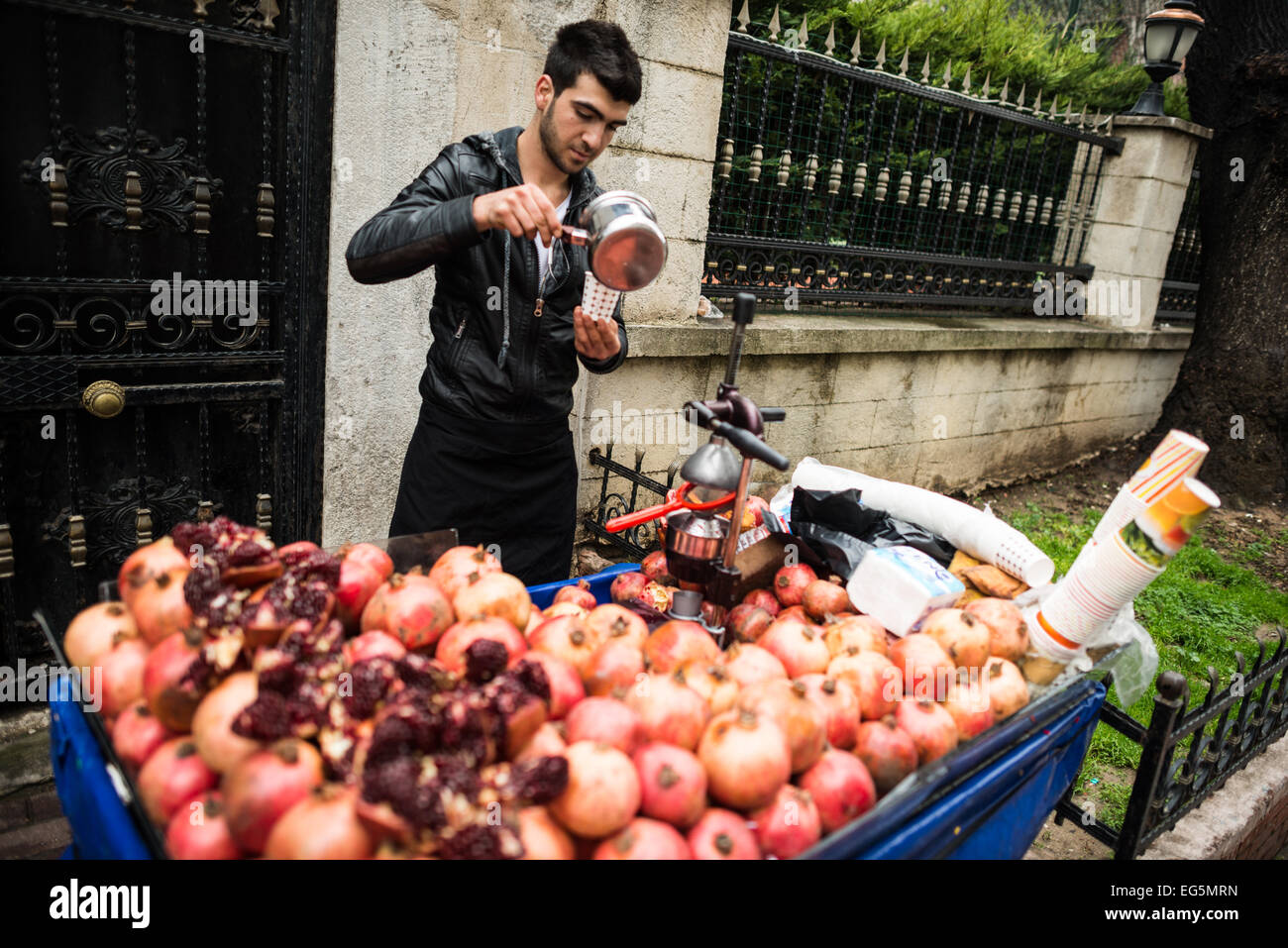 Un uomo vende spremuta di succo di melograno dal suo carrello ad Istanbul in Turchia. Foto Stock