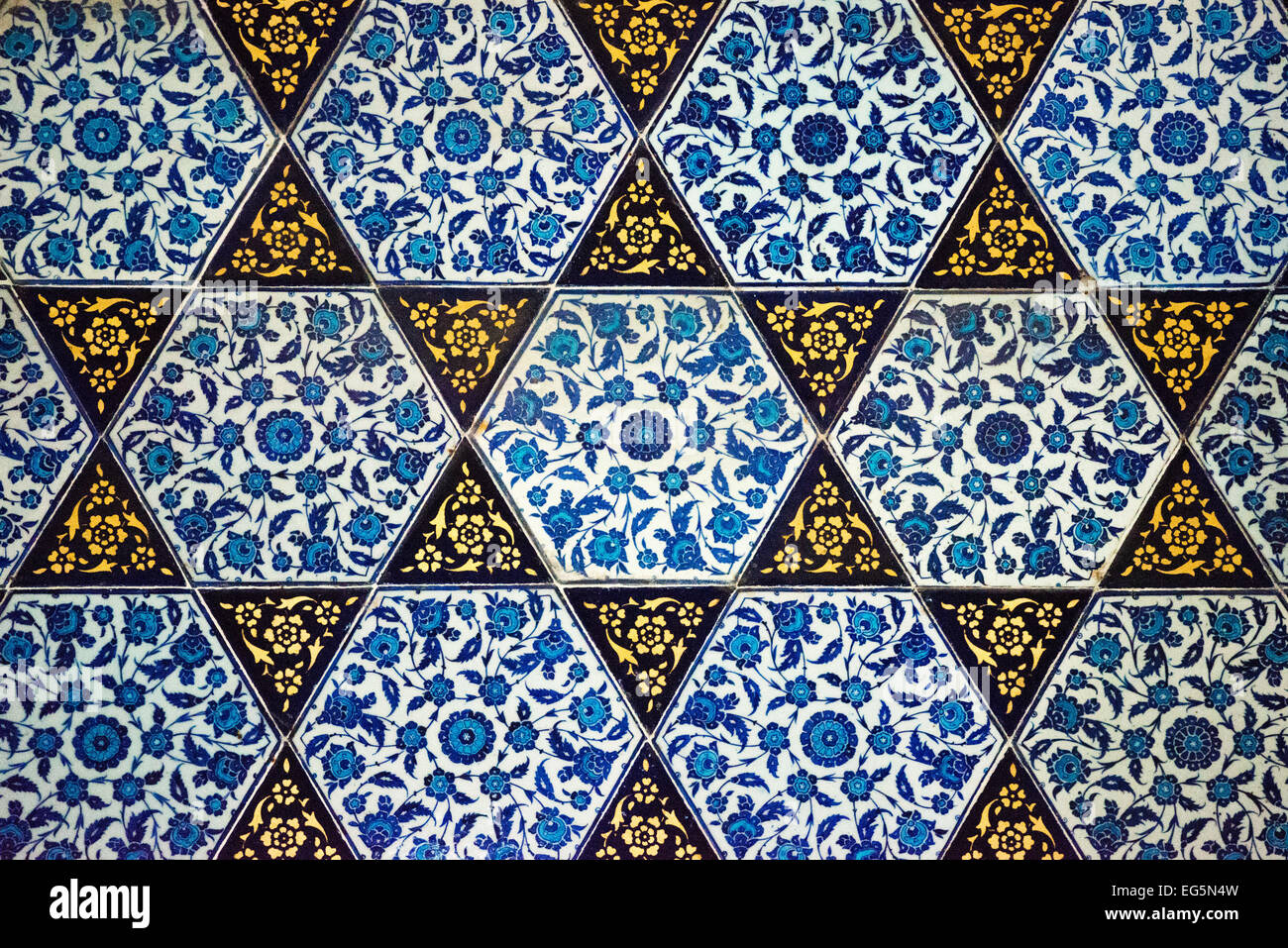 Decorazioni dell'Enderun del Palazzo Topkapi Istanbul Turchia | ISTANBUL — Piastrelle esagonali a sfumature dorate a forma di stella formano un campo geometrico fitto nell'Enderun del Palazzo Topkapi, ogni segmento triangolare riempito con un lavoro floreale a volute blu cobalto. Il motivo riflette il vocabolario decorativo più ampio della corte ottomana, che univa il design geometrico islamico agli idiomi floreali sviluppati dalle botteghe di ceramica di İznik. Foto Stock