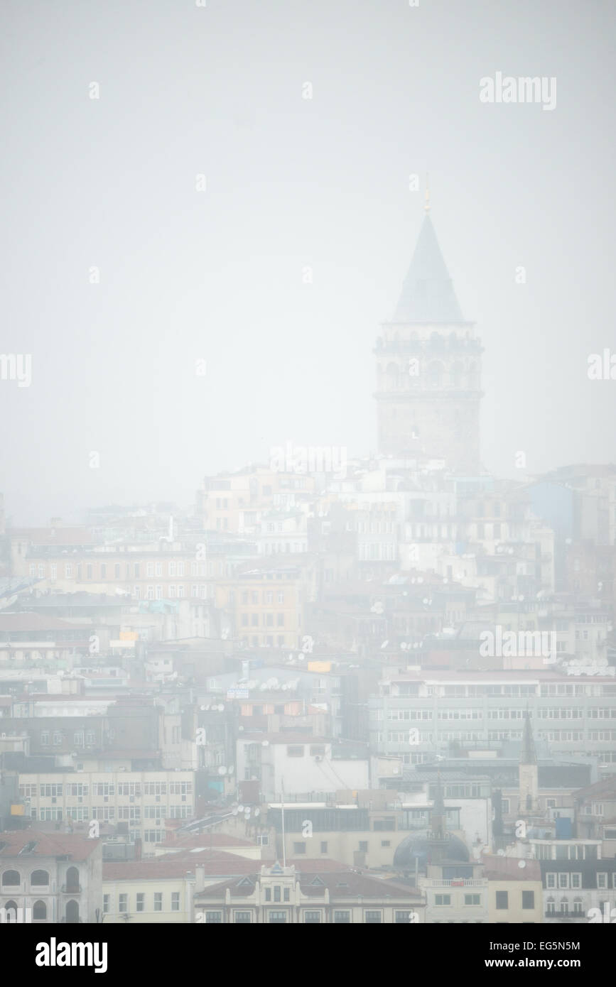 ISTANBUL, Turchia / Türkiye - la sagoma della Torre Galata emerge attraverso una fitta nebbia, vista dal Palazzo Topkapi. Questa suggestiva scena cattura la torre storica, un punto di riferimento del quartiere Beyoğlu di Istanbul, appena visibile attraverso il Corno d'Oro dal punto panoramico dell'ex residenza imperiale ottomana. Foto Stock