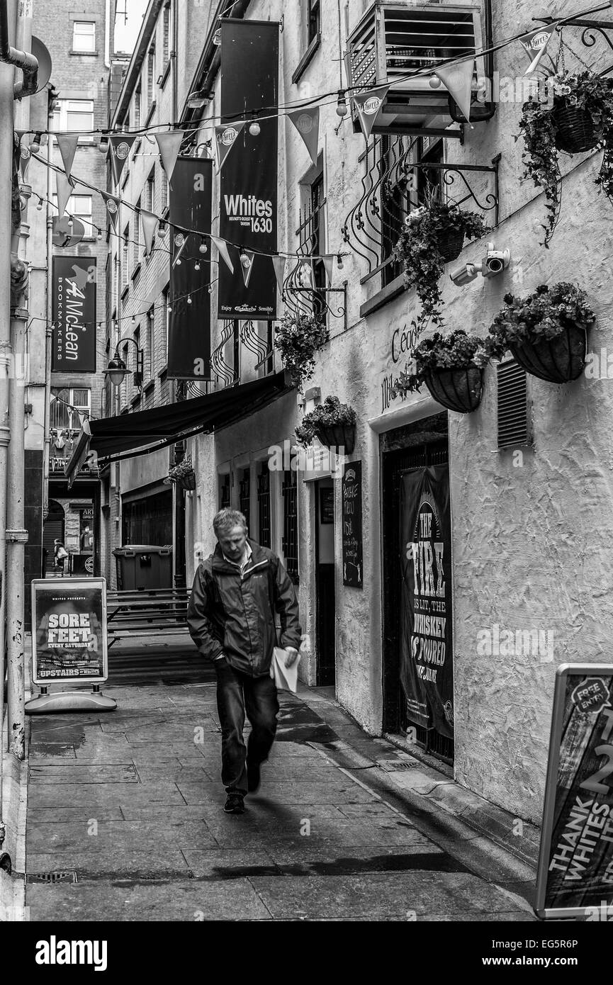 Un uomo a piedi attraverso cantina entrata a Belfast. La fotografia è reso come monocromatico. Foto Stock