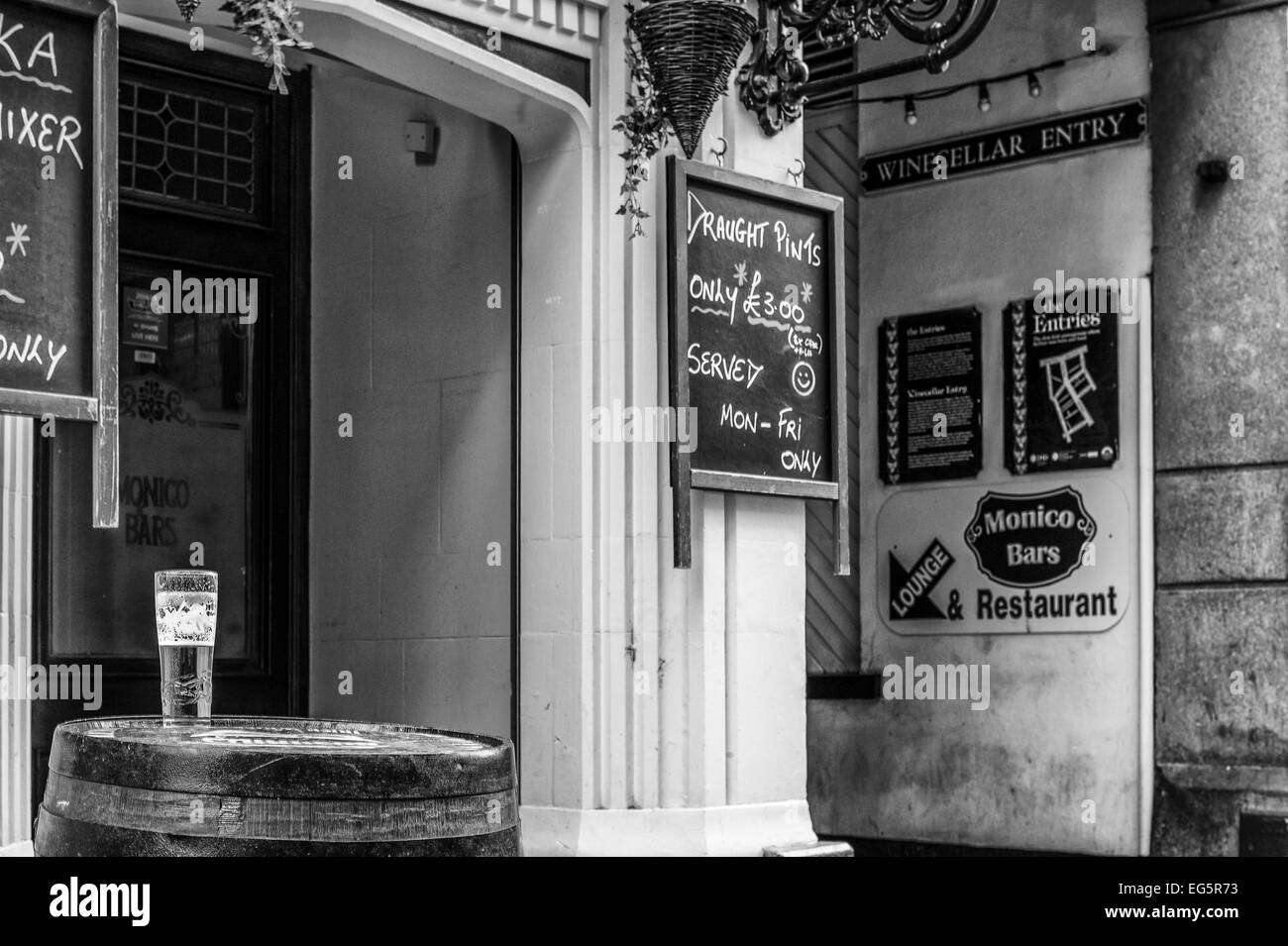 L'ingresso alla cantina entrata di Belfast. Da un lato sulla cima di un barile è una mezza consumata pinta di birra. Monocromatico. Foto Stock