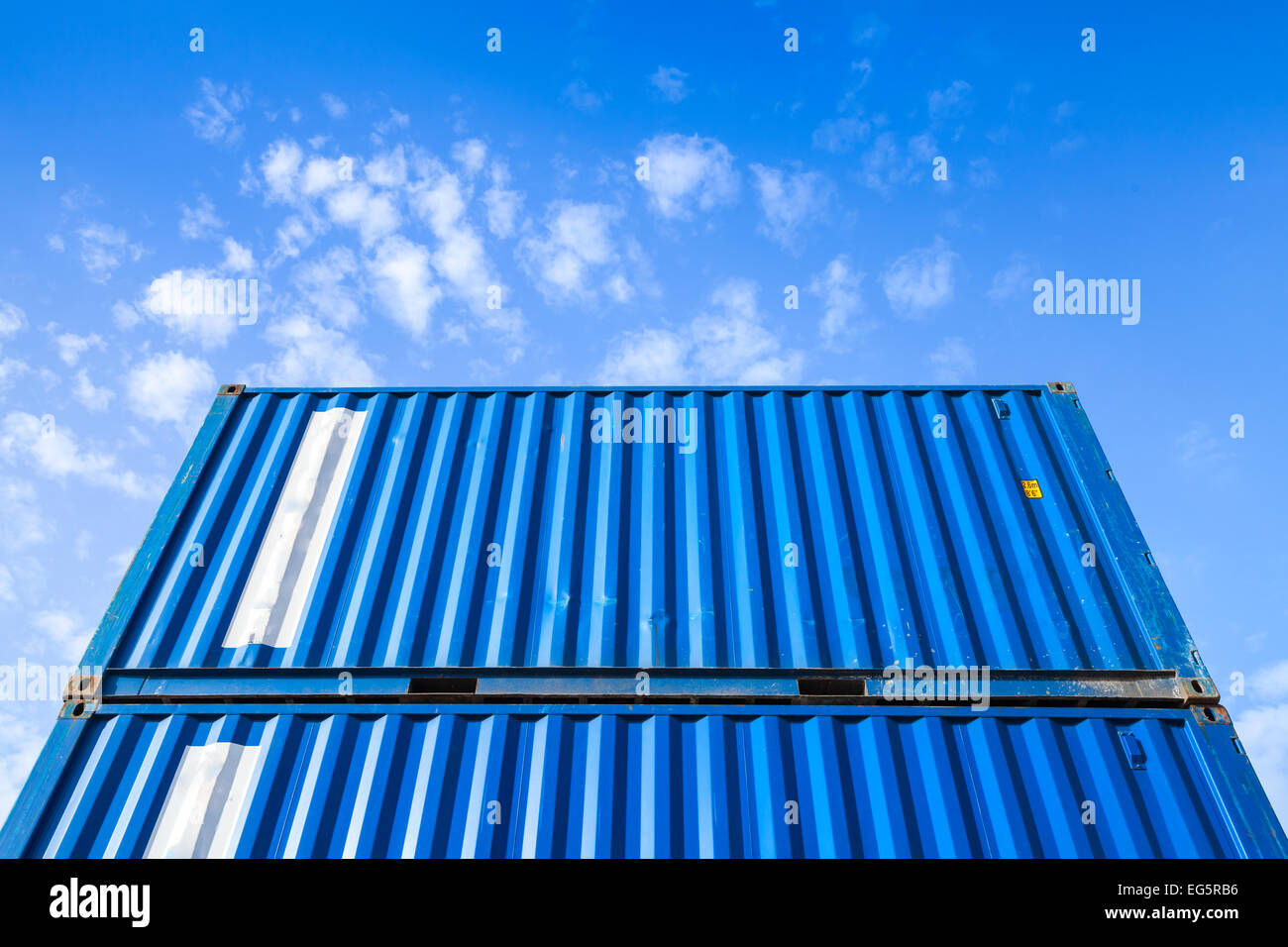 Blu acciaio carico industriale contenitori vengono impilati nell'area di memorizzazione Foto Stock