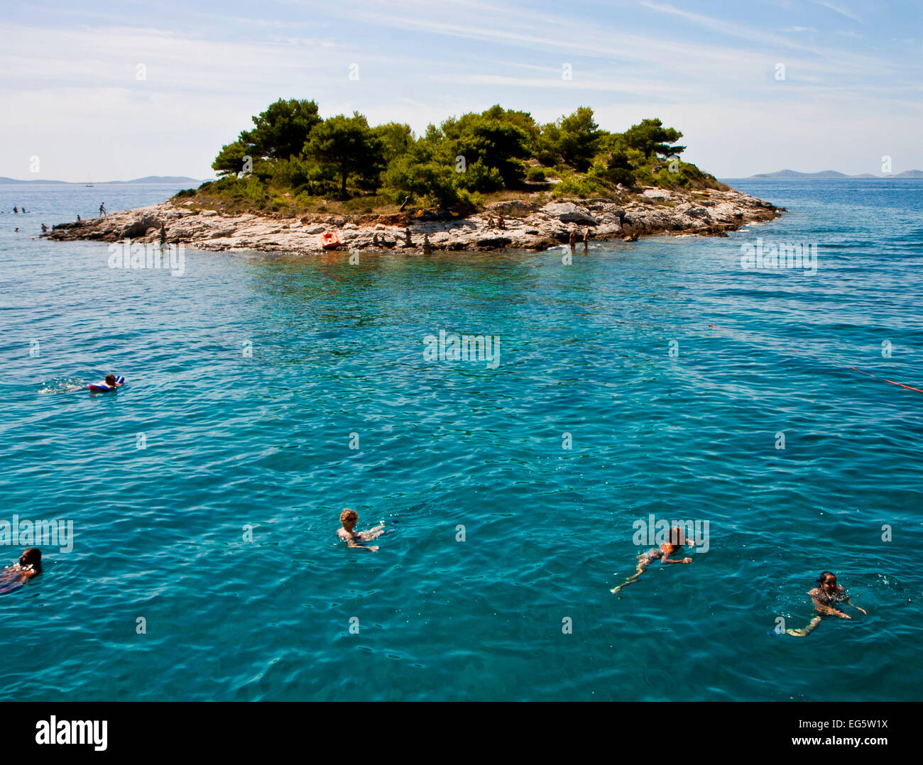 Croaia, costa dalmata: turisti nuotare tranquillamente in Adriatico blu del mare nei pressi di una piccola isola dell' arcipelago di Murter Foto Stock