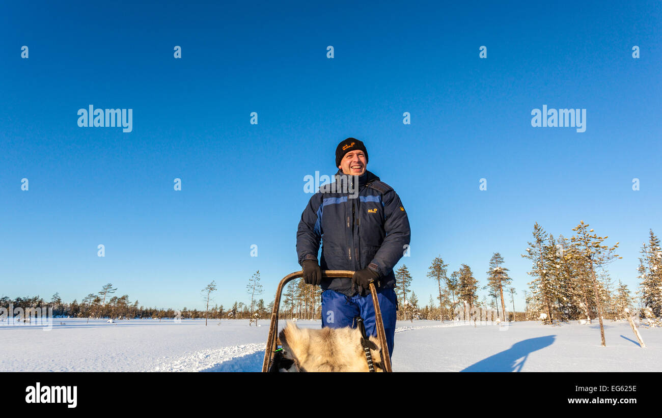 Un uomo su un cane di gite in slitta attraverso un paesaggio invernale nel nord Europa, Lapponia, Finlandia, Lapponia, Europa Foto Stock