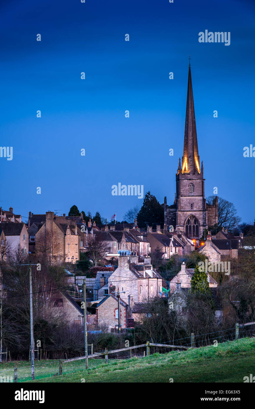 Tetbury, Gloucestershire, UK. 17 Febbraio, 2015. Le luci sulla guglia di 'St. Maria la Vergine' sfarfallio su come il sole scende al di sotto del trend con orizzonte di riferimento e la temperatura scende a Tetbury, Gloucestershire, Inghilterra. Credito: Terry Mathews/Alamy Live News Foto Stock