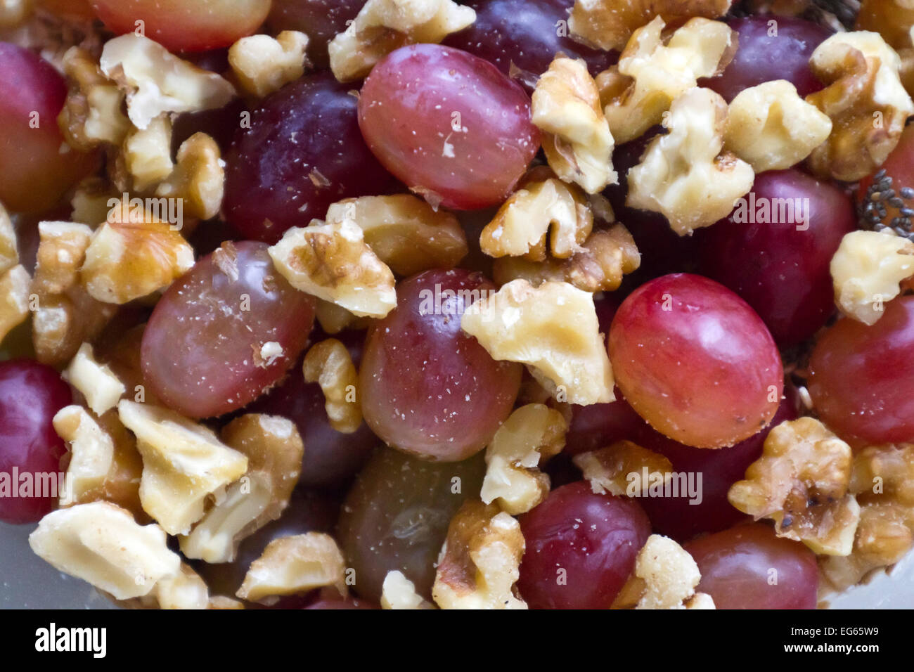 Close up di un snack sano mix di maturazione uve rosse, nere chia semi e noci di greggio Foto Stock