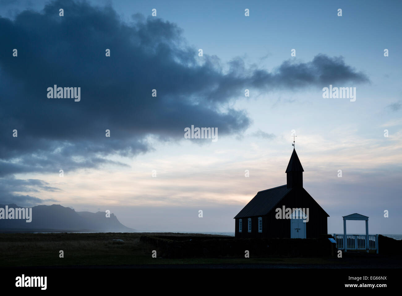 Cielo drammatico sulle montagne e la chiesa nera a Budir Islanda Foto Stock