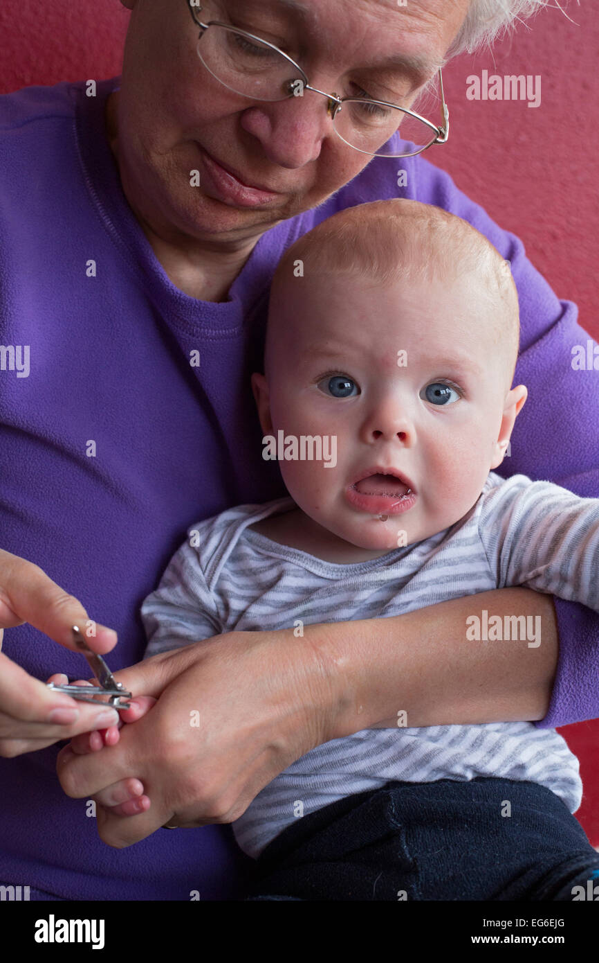 Denver, Colorado - sette-mese-vecchio Adamo Hjermstad Jr. grida come sua nonna, Susan Newell, tagli suo le unghie. Foto Stock