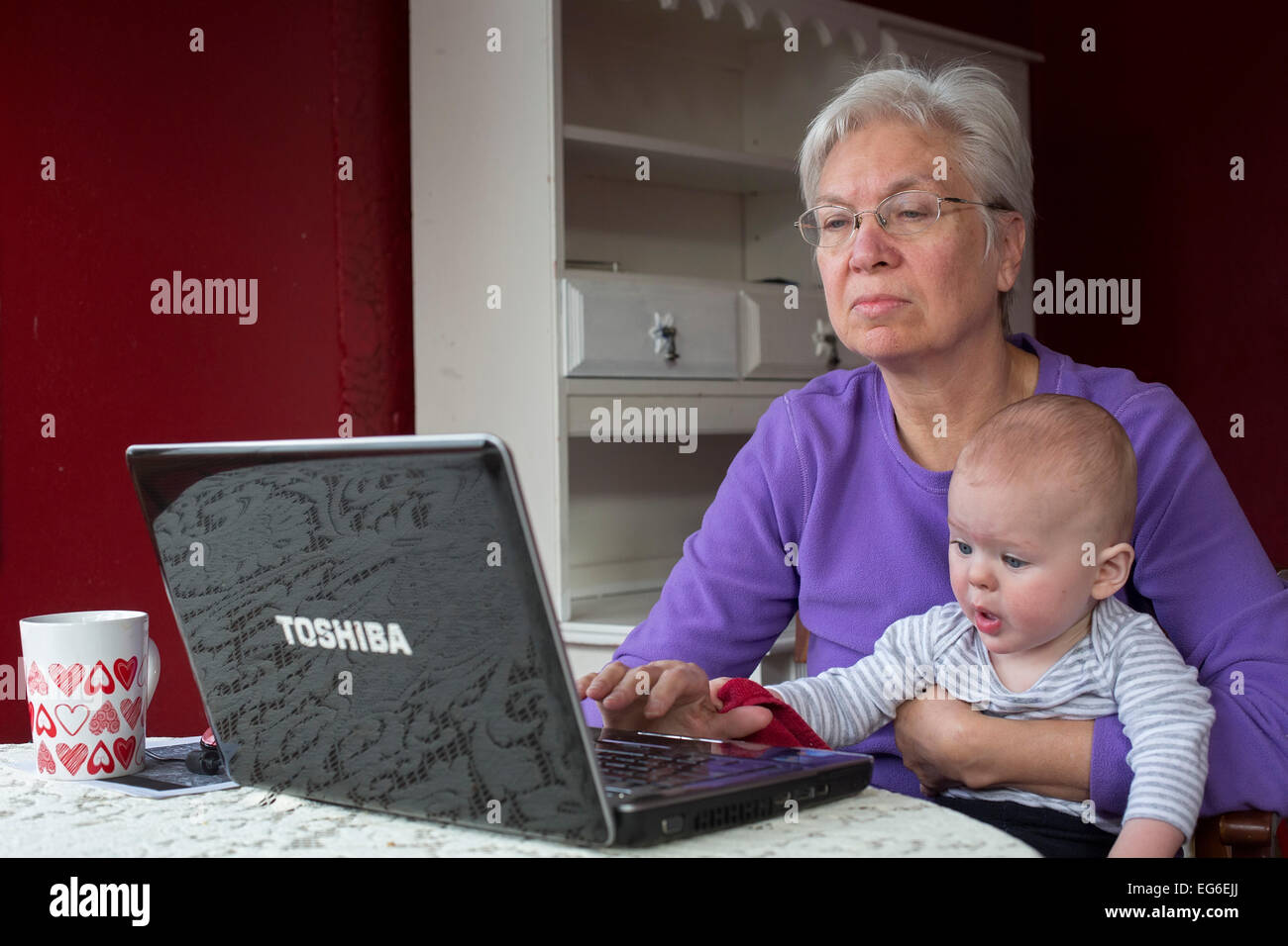 Denver, Colorado - sette-mese-vecchio Adamo Hjermstad Jr. aiuta la sua nonna, Susan Newell, 66, come lavora su un computer. Foto Stock