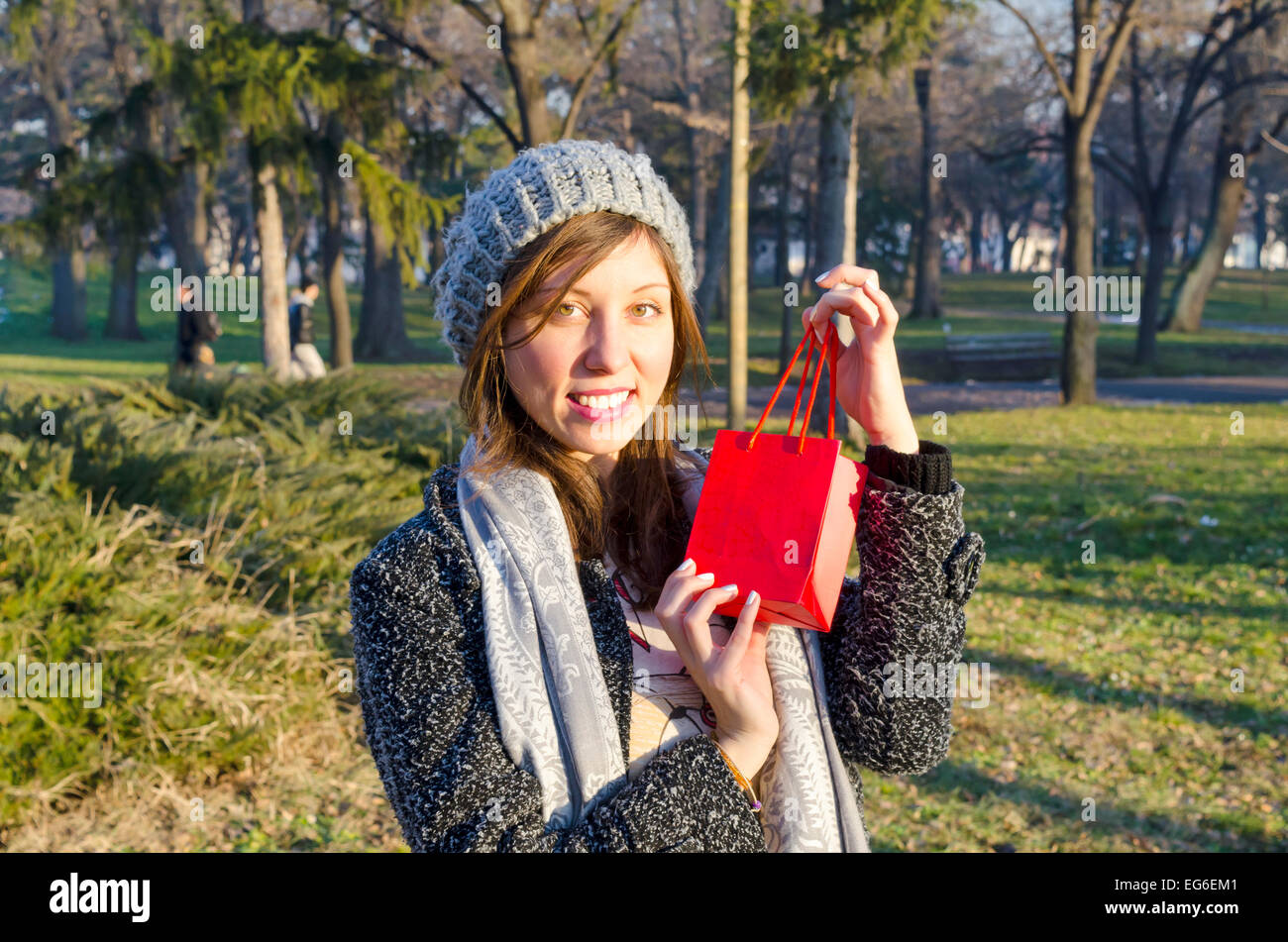 Sorpreso ragazza in posa con una confezione regalo rossa in un parco Foto Stock