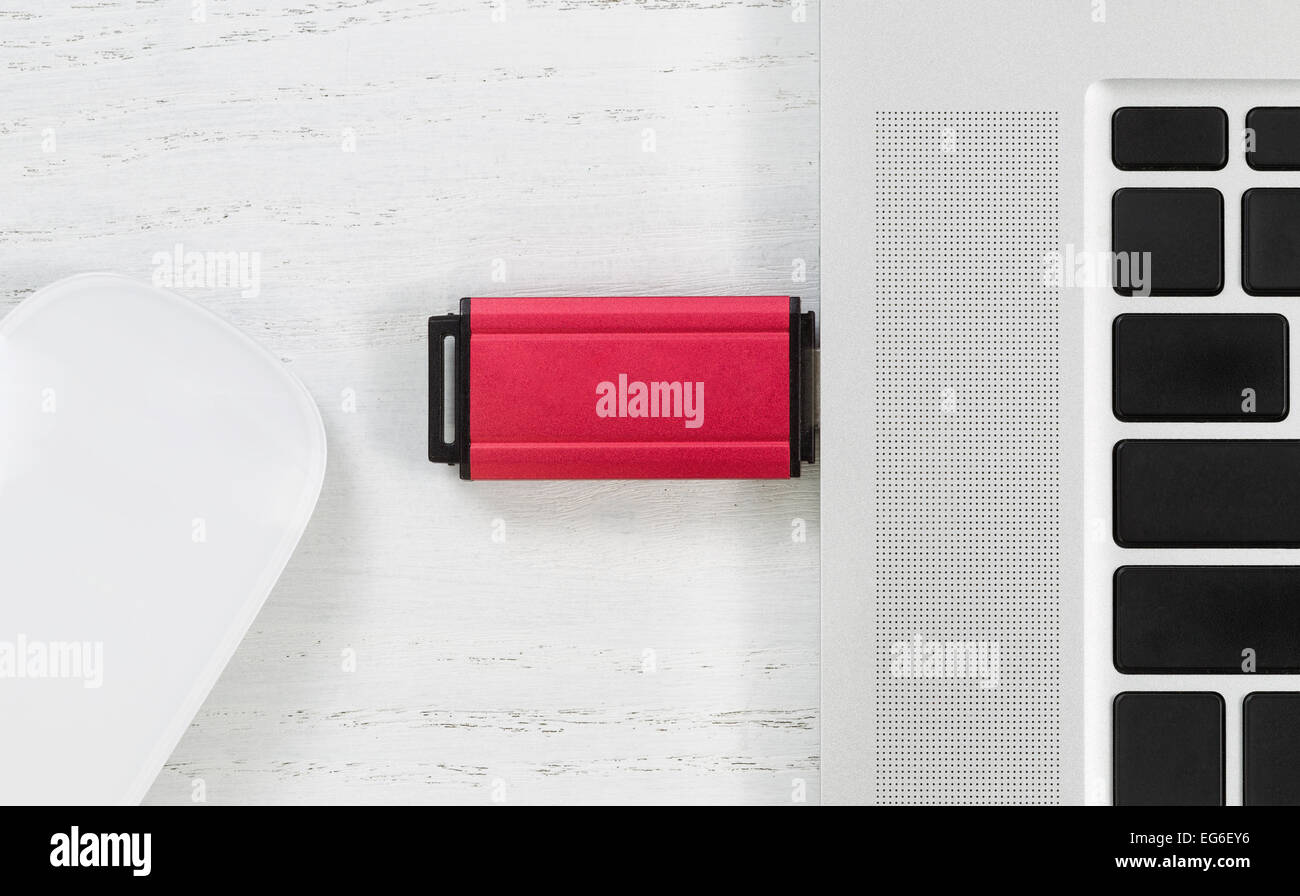 Parte superiore inclinata visualizza immagine di colore rosso thumb drive portatile nella porta USB e il mouse sul desktop bianco. Concetto di sicurezza Foto Stock Parte superiore inclinata visualizza immagine di colore rosso thumb drive portatile nella porta USB e il mouse sul desktop bianco. Concetto di sicurezza Foto Stock