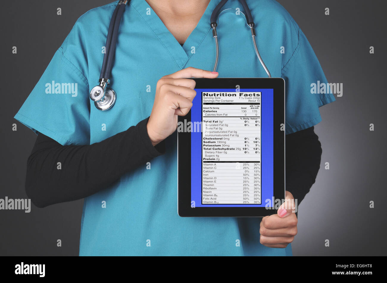 Primo piano di una femmina di professionista medico tenendo un computer tablet con un blu dello schermo a griglia e una etichetta nutrizionale. Foto Stock