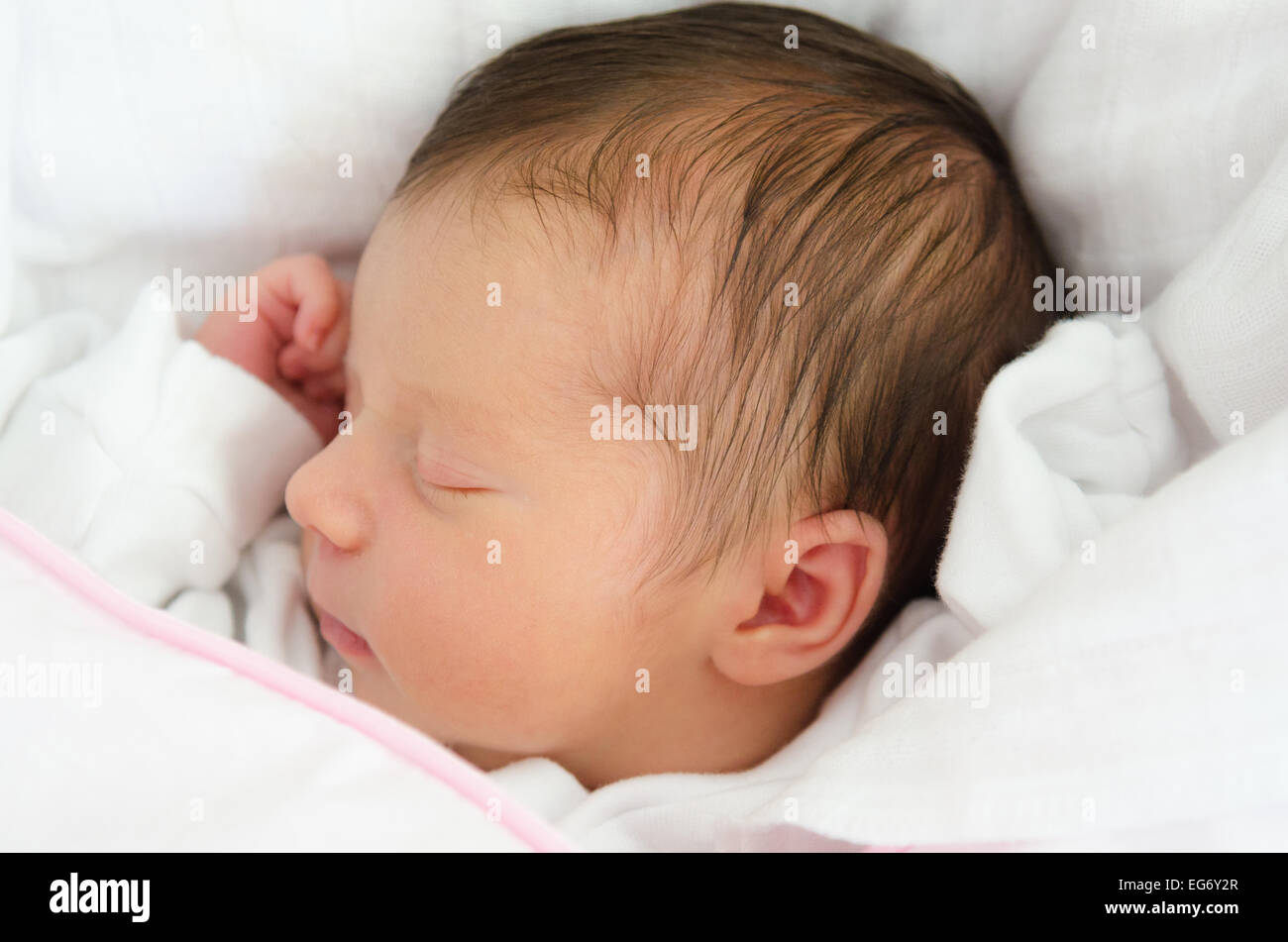 La faccia di un sonno neonato in biancheria da letto bianca Foto Stock