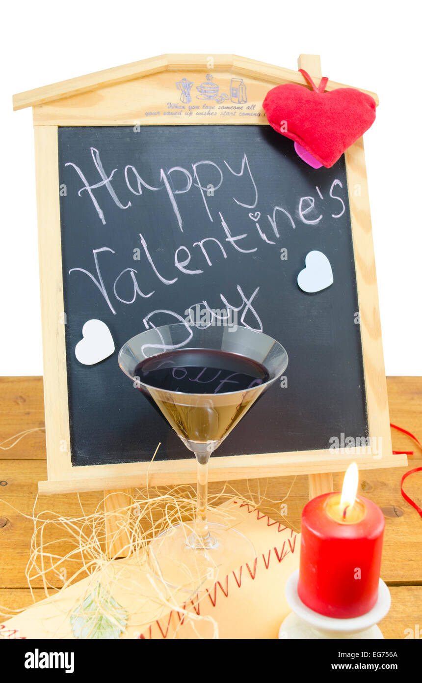 Lavagna a fogli mobili con le parole Happy Valentines scritto su di esso, decorata con cuori, una candela e un bicchiere di vino Foto Stock