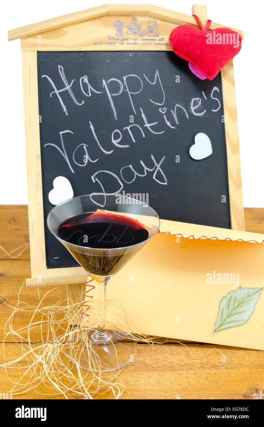 Lavagna a fogli mobili con le parole Happy Valentines scritto su di esso, decorata con cuori, una candela e un bicchiere di vino Foto Stock