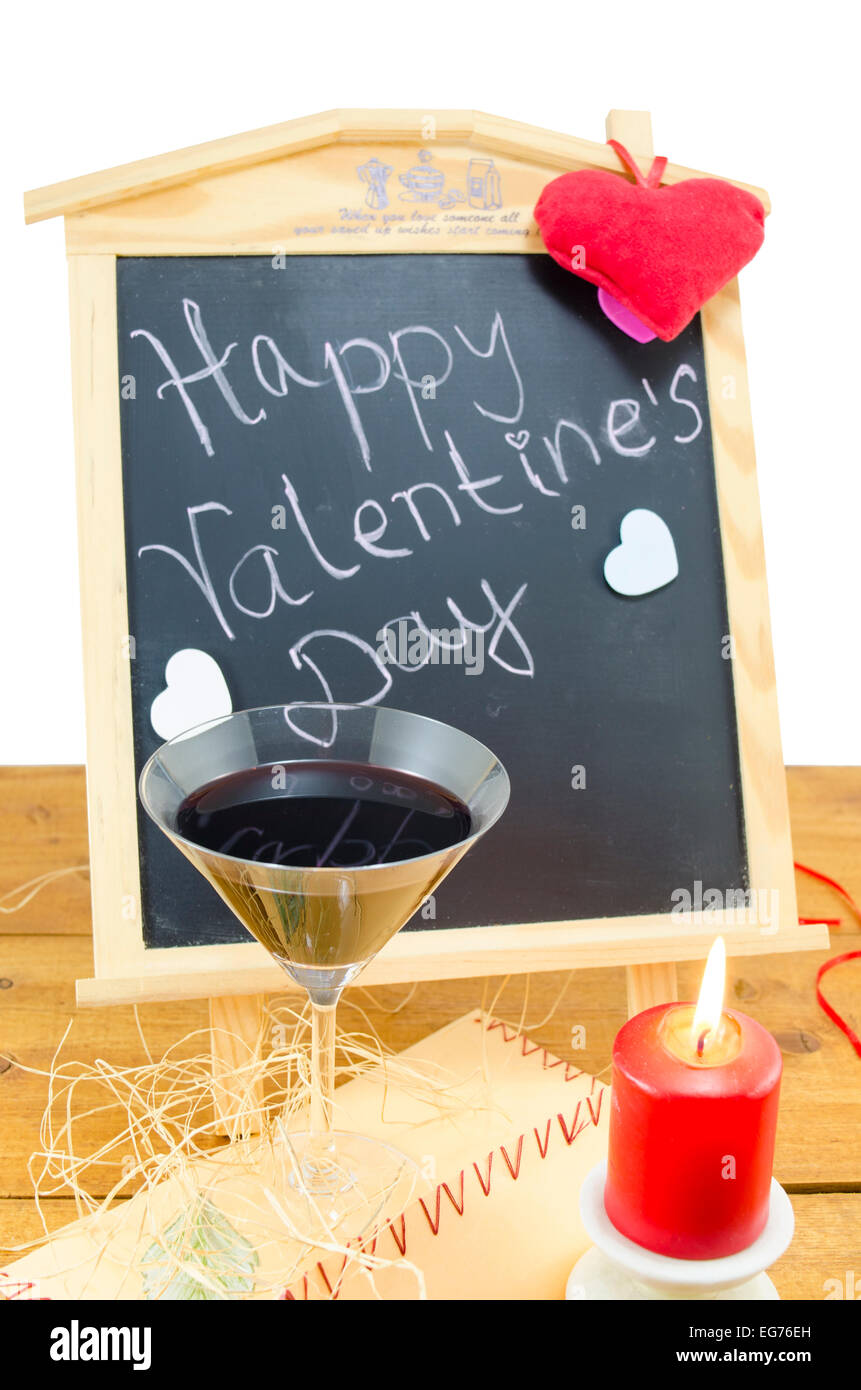 Lavagna a fogli mobili con le parole Happy Valentines scritto su di esso, decorata con cuori, una candela e un bicchiere di vino Foto Stock